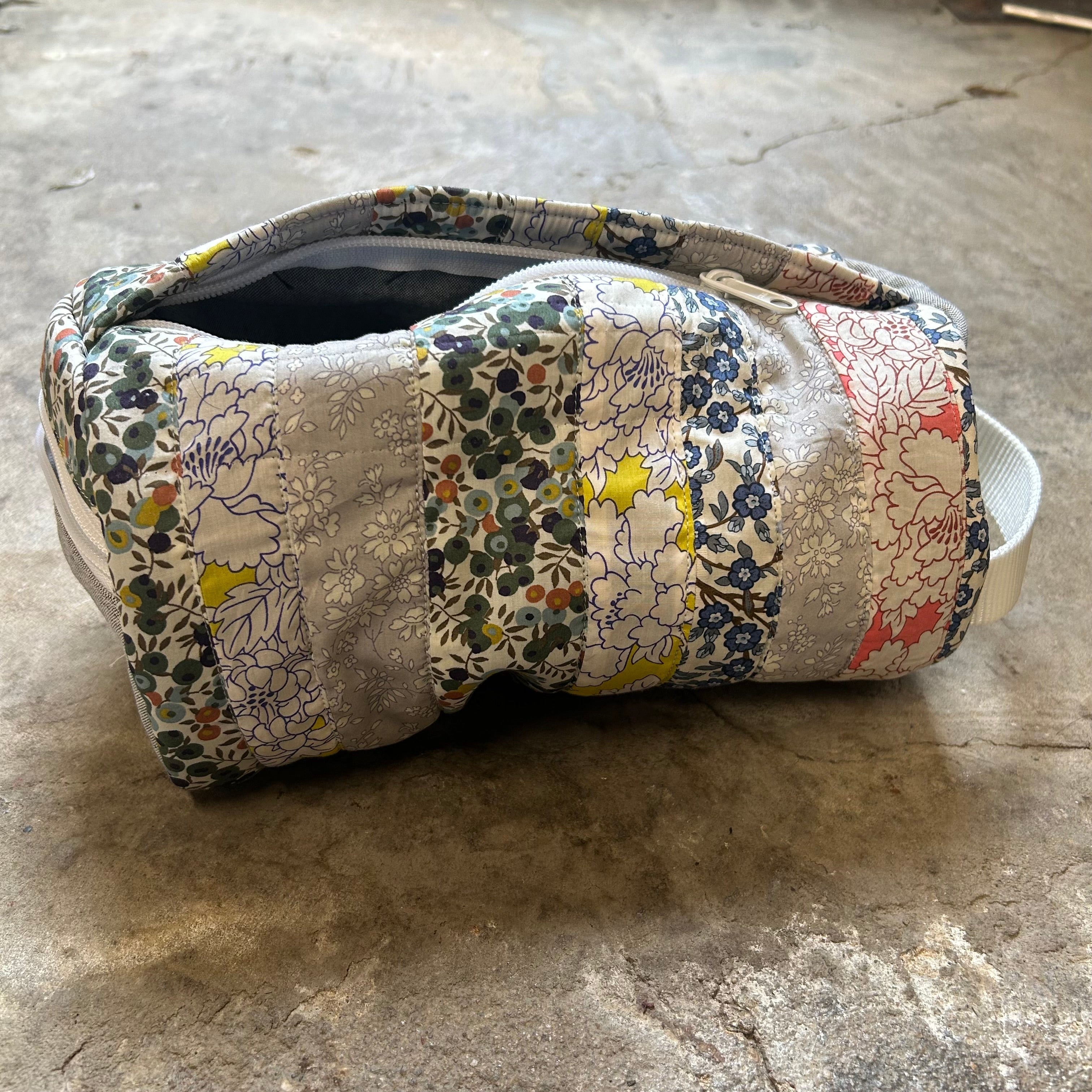 Opened zipper round quilted floral bag.