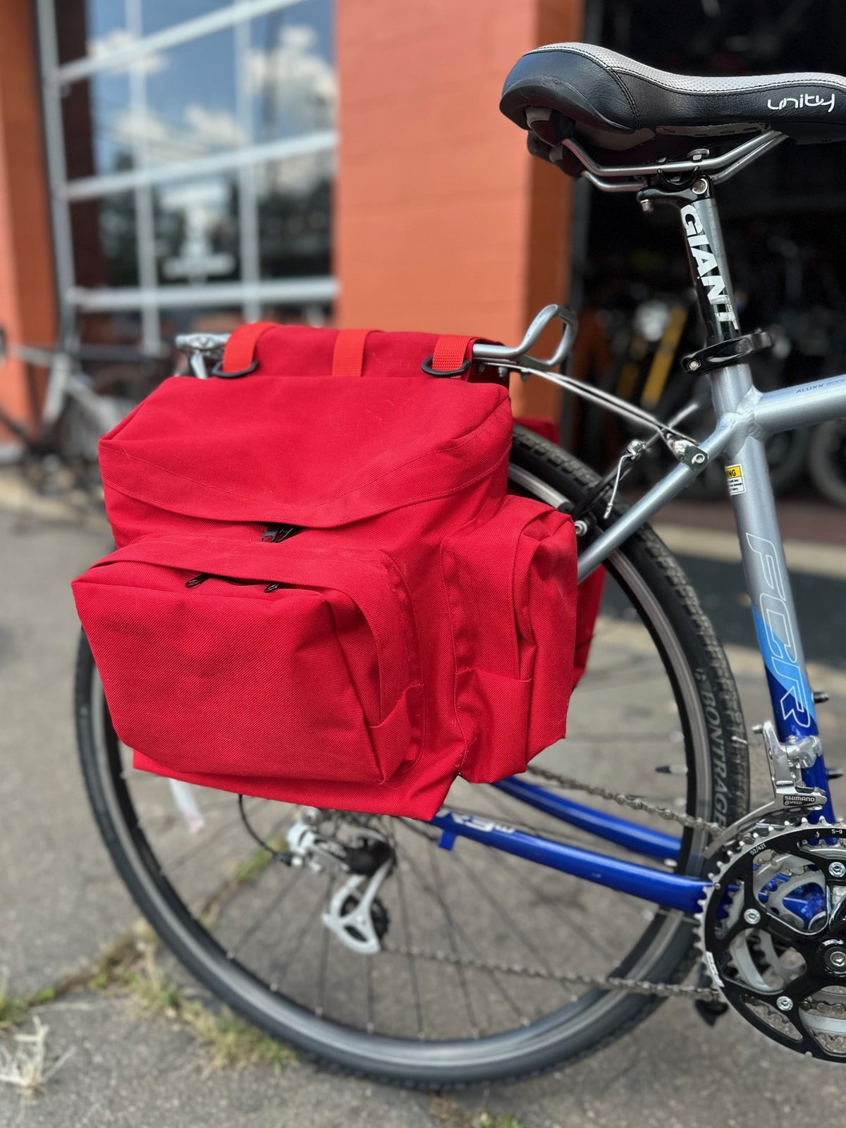 red saddle bag on the back of a bicycle outside a bike shop