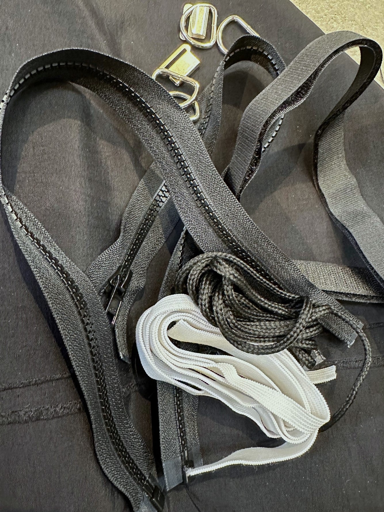 two zippers, velcro, cording, Drings, and white elastic with black fabric
