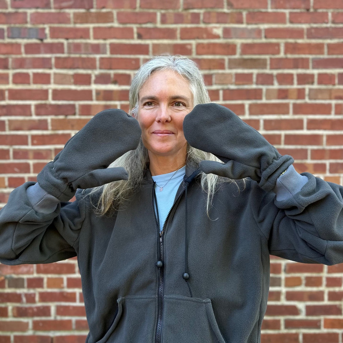 close up of a woman with grey fleece mittens, grey sweatshirt