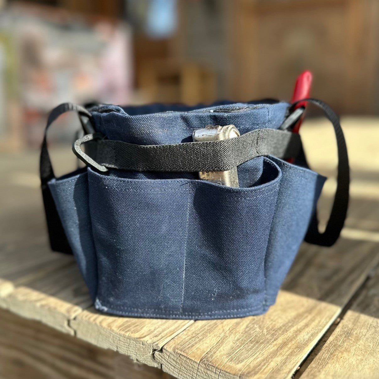 Blue tool pouch with tools on a wooden surface