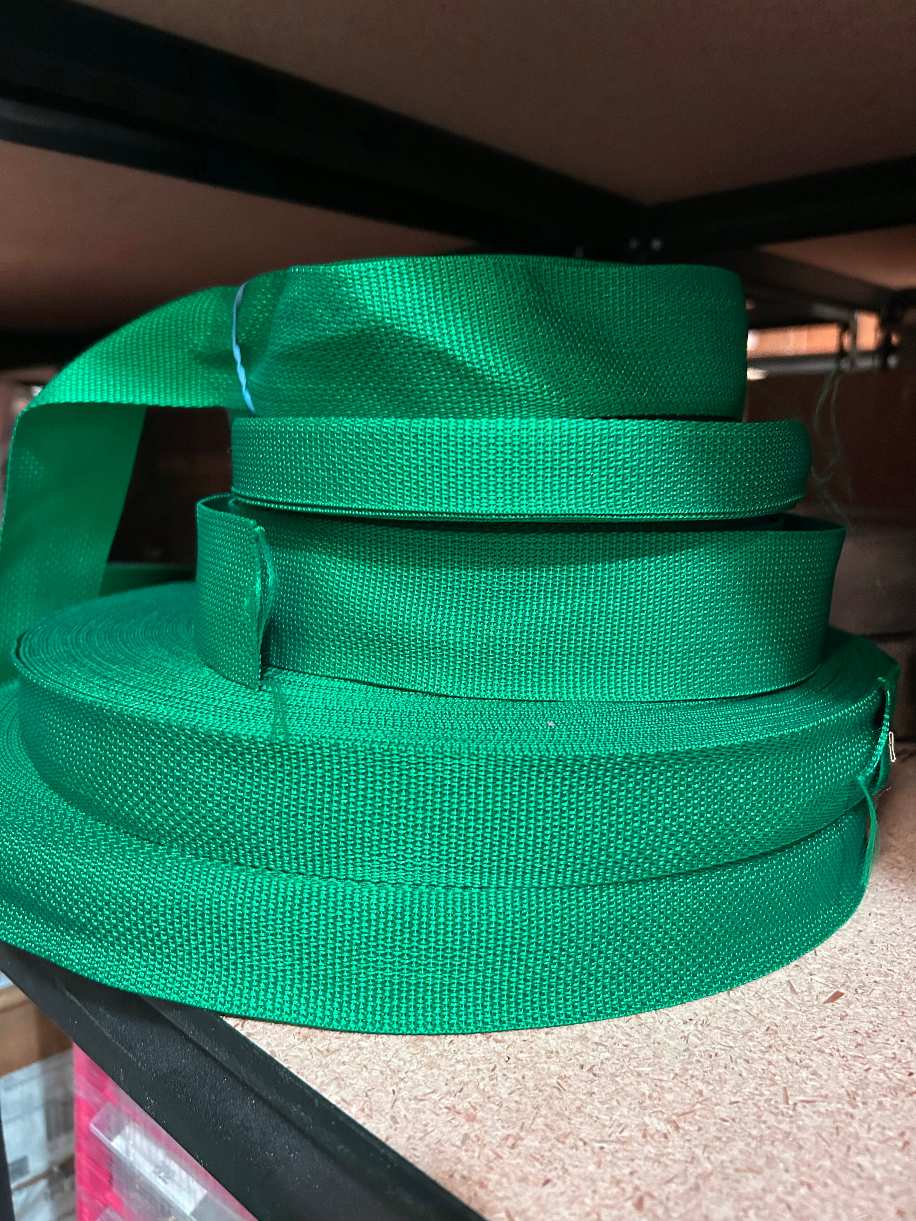 Green webbing strap stacked on a surface with a blurred background