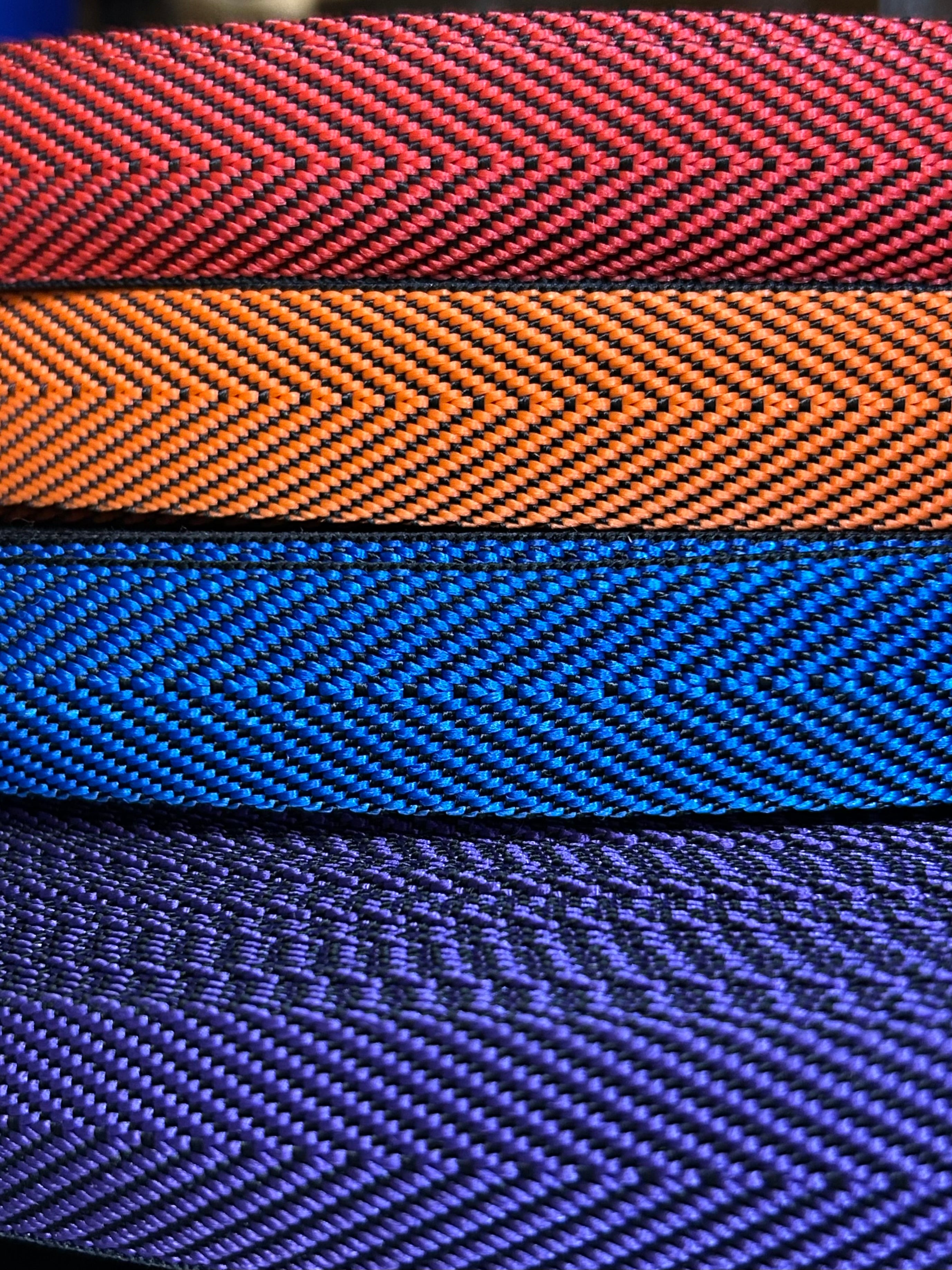 Close-up of four herringbone webbing in red, orange, blue and purple.