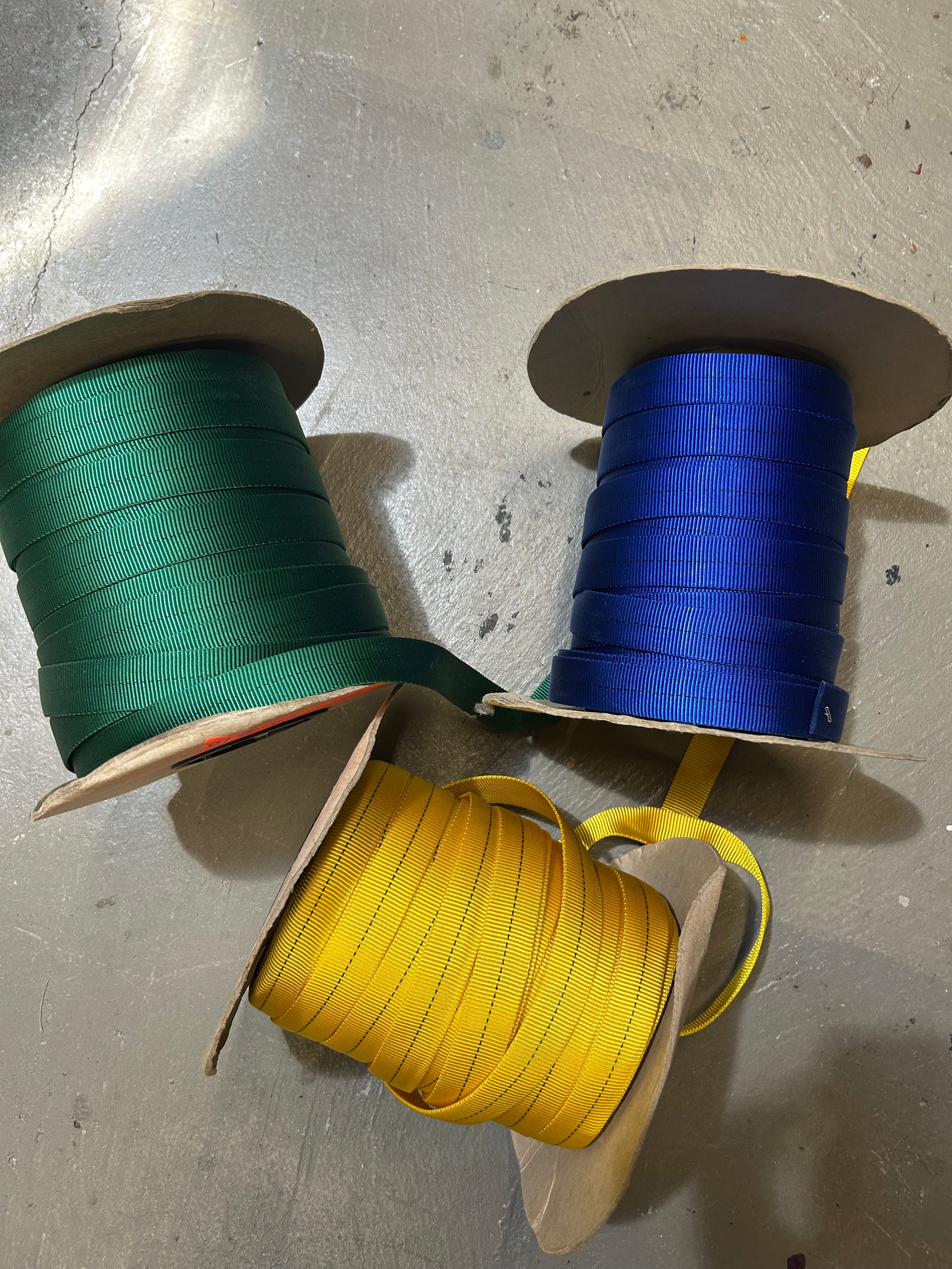 Three rolls of tubular webbing in green, blue, and yellow