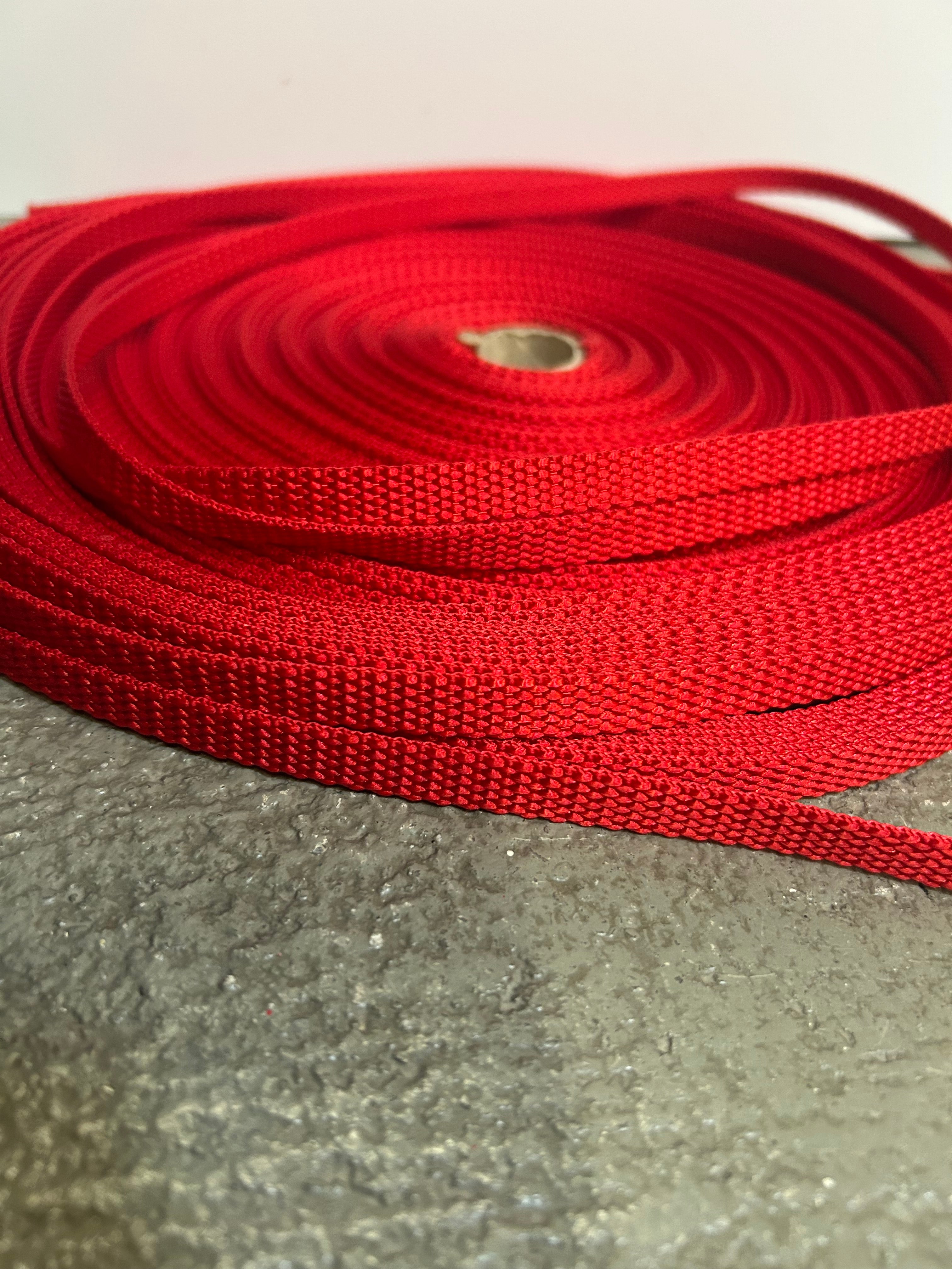 Red webbing strap coiled on a concrete surface