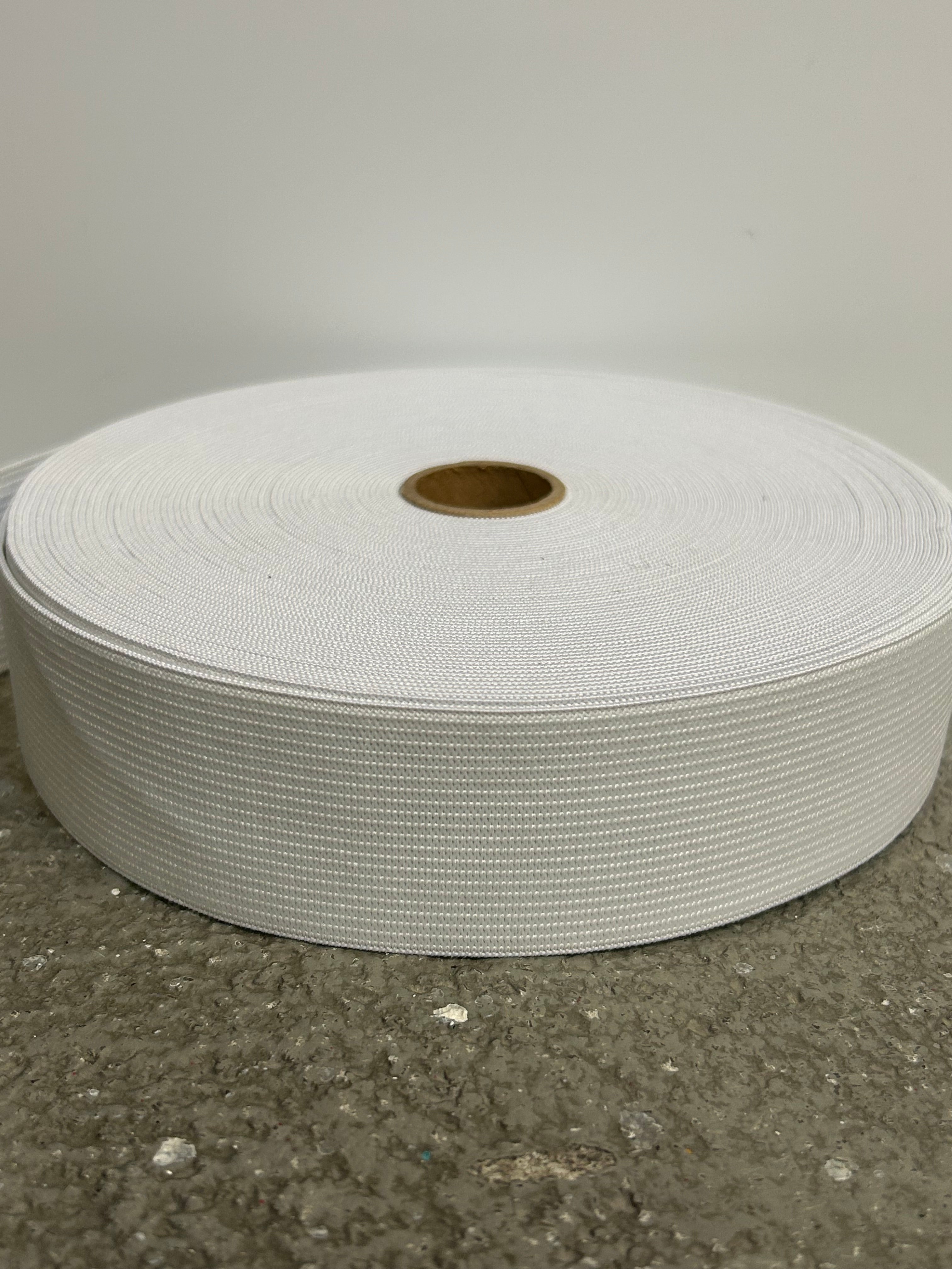 Roll of white elastic webbing on a textured surface
