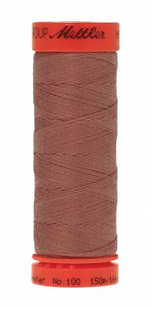 A spool of Mettler sewing thread in a dusty rose or mauve-brown shade, with a bright orange-red top and bottom cap, isolated on a white background.