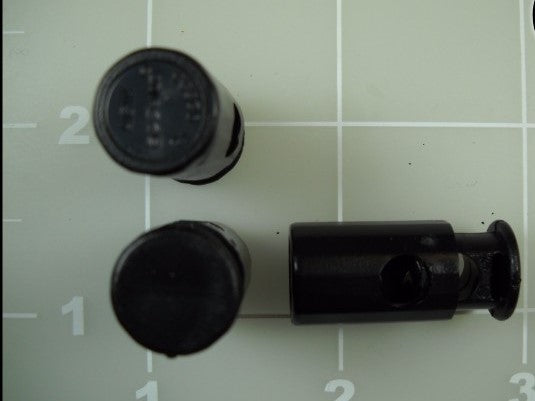 Three black toggle locks with springs on a measuring mat.