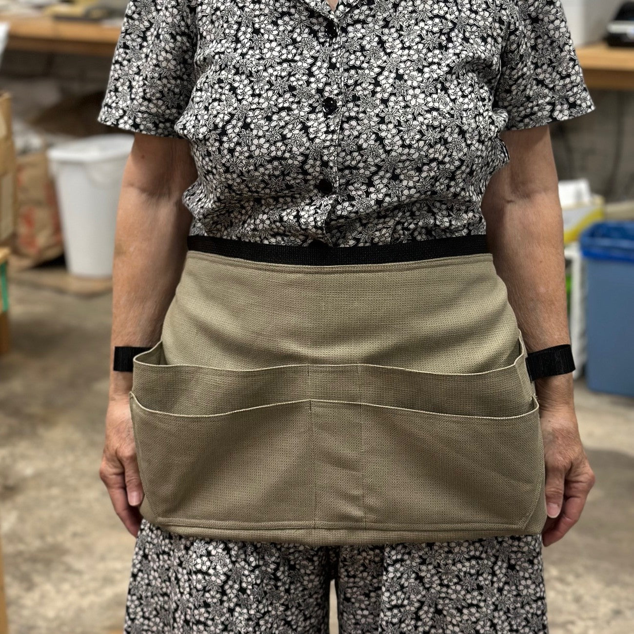 Close up of Woman wearing a black and white top and a tan tool belt