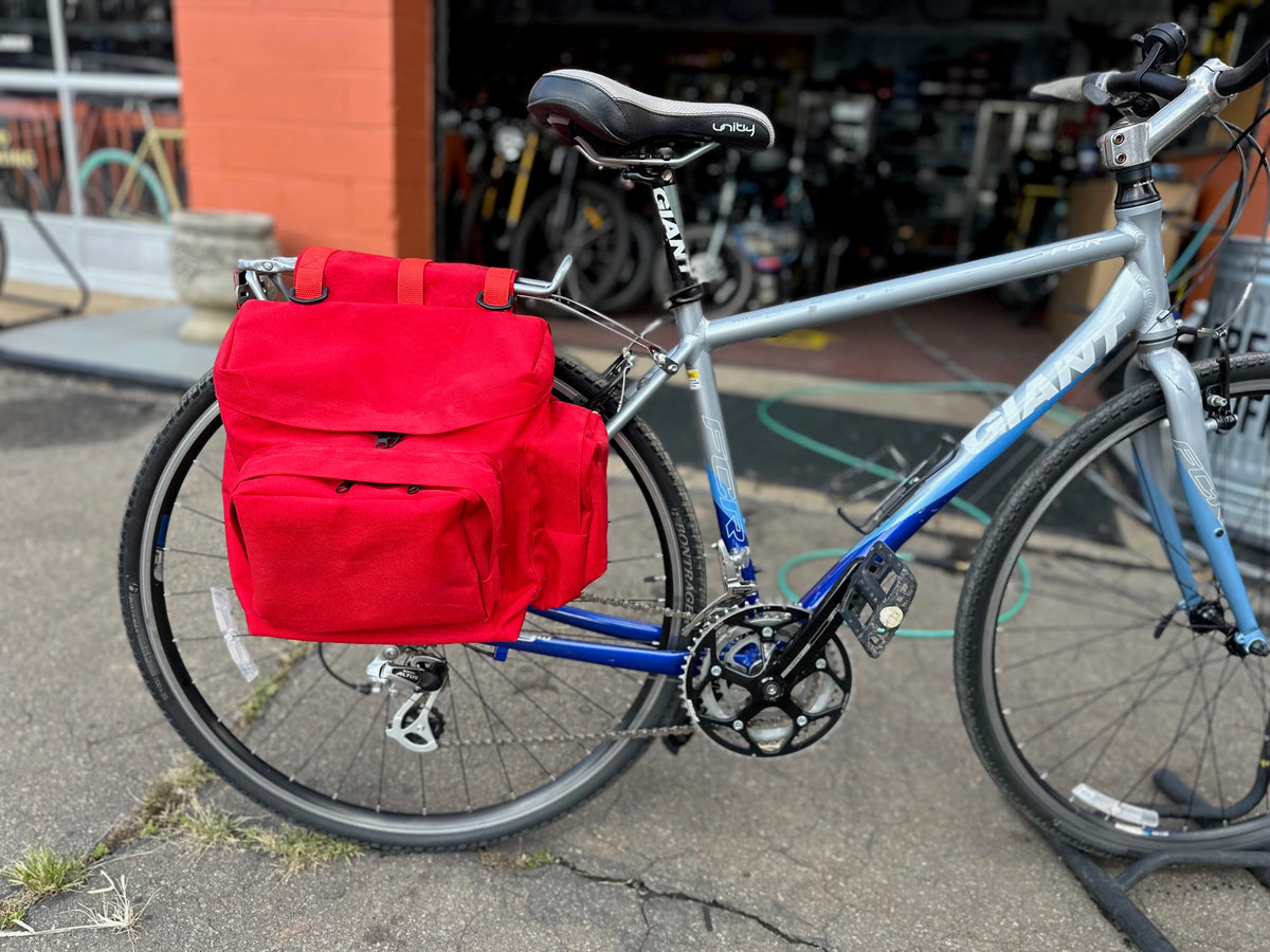 red saddle bag on the back of a bicycle outside a bike shop