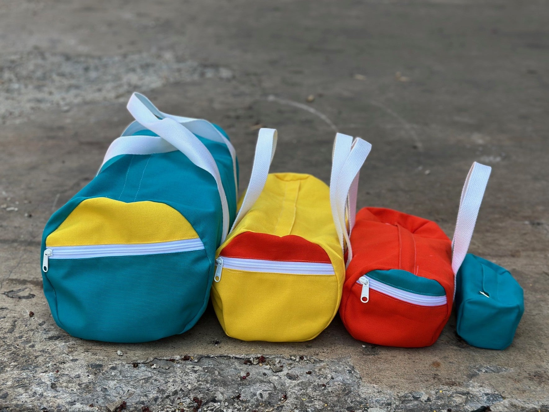 Four colorful bags with zippers on a concrete surface