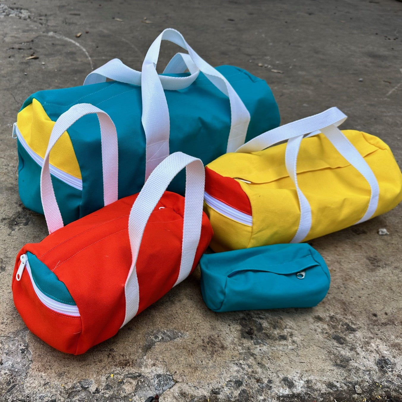 Four colorful duffel bags on a concrete surface