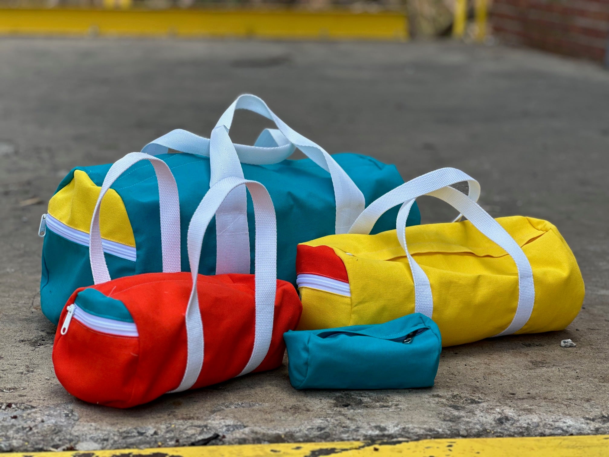 Colorful duffel bags on a concrete surface with a blurred background