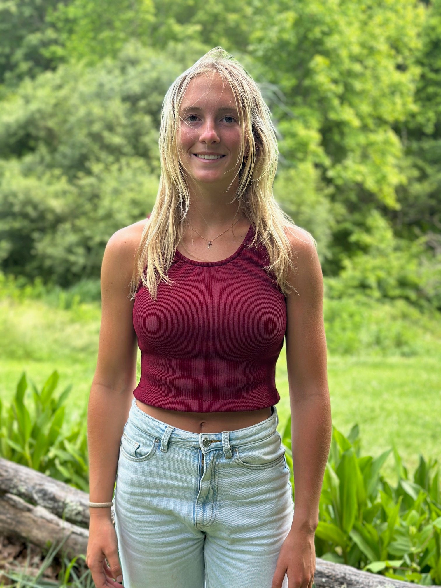 Woman standing outside wearing a red tankini and jeans