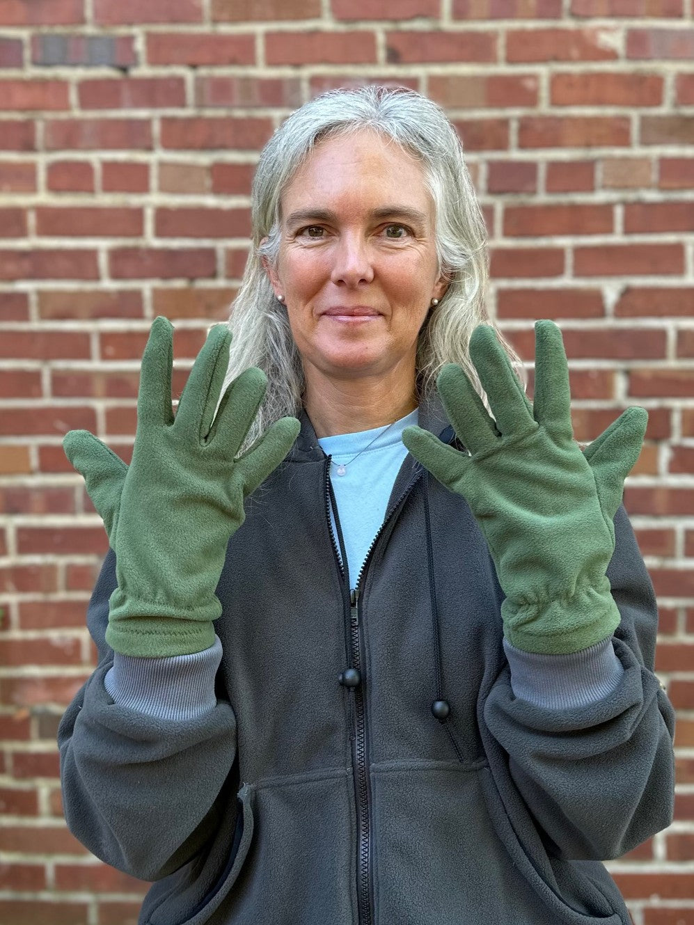 close up of a person with green fleece gloves, grey sweatshirt