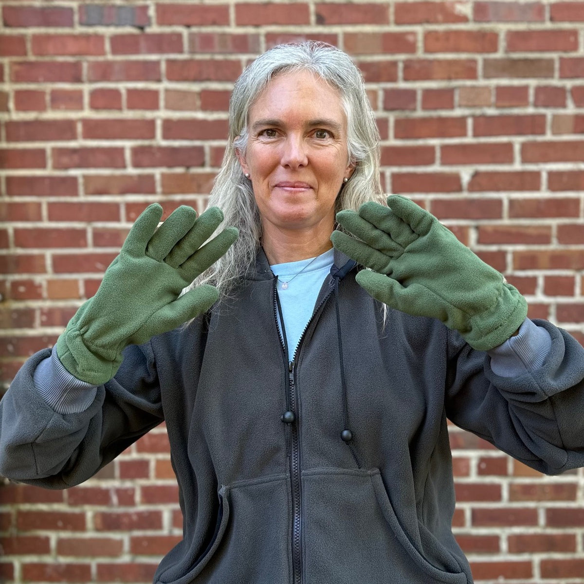close up of a person with green fleece gloves, grey sweatshirt