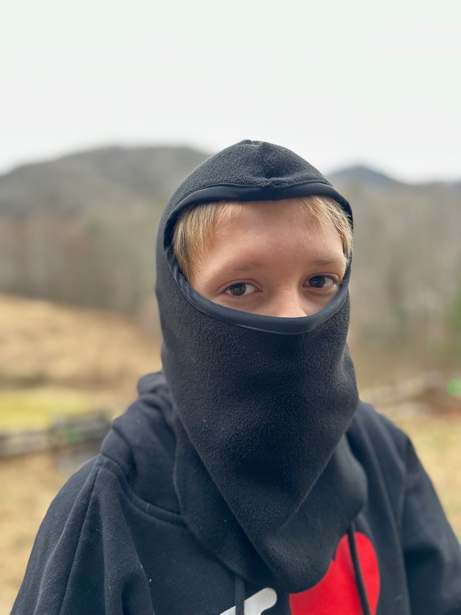 Boy wearing a black fleece balaclava outside