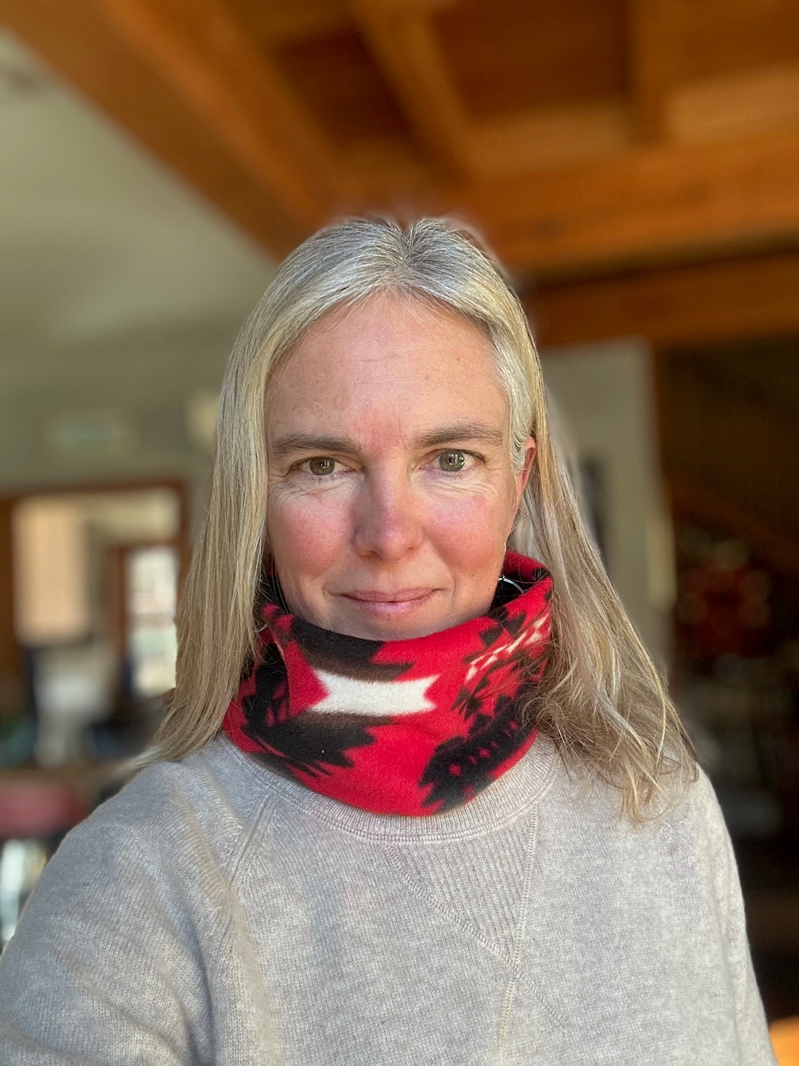 woman wearing a red, black, and white fleece neckwarmer with a grey sweater
