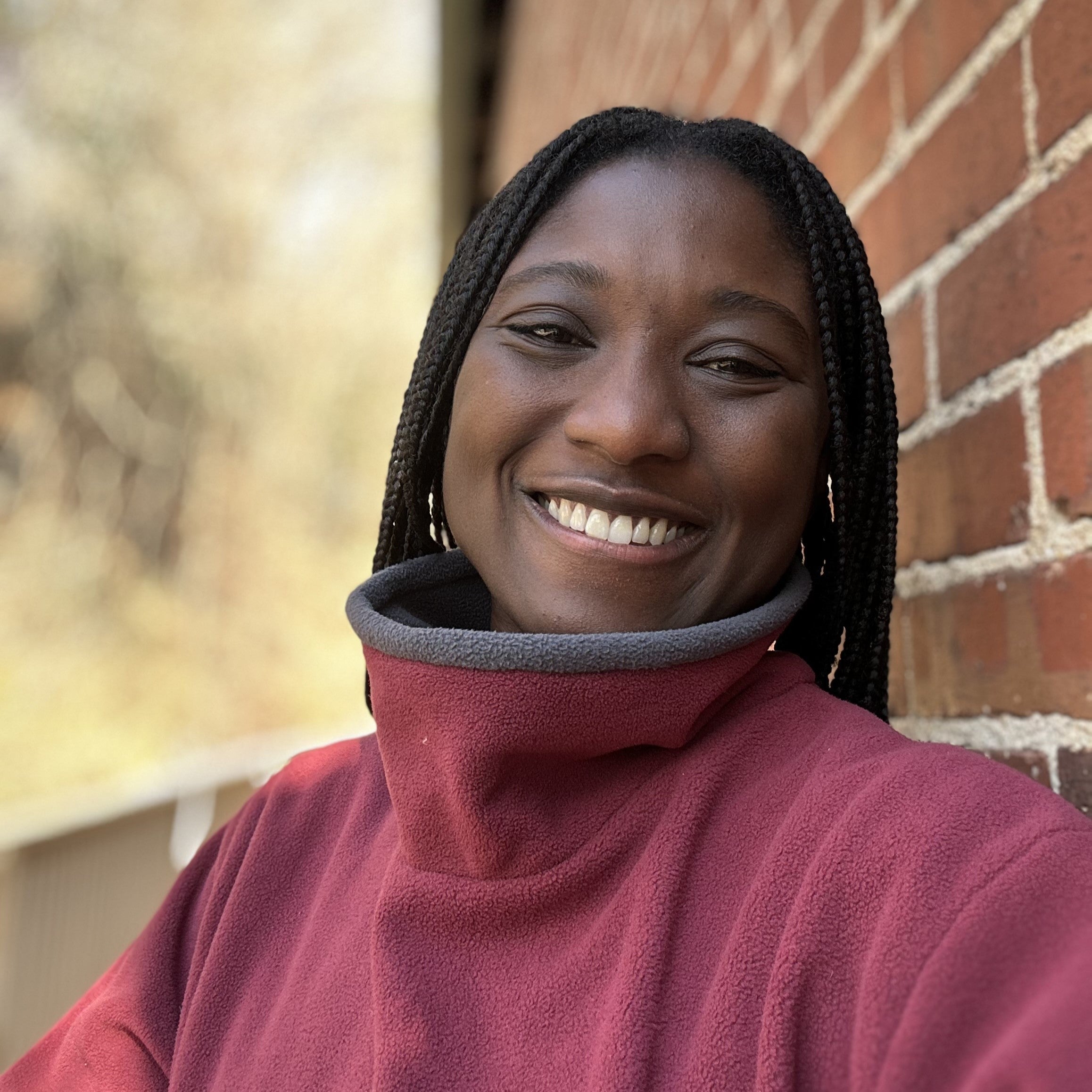 Close up of Black woman wearing a red mock fleece sweater smiling