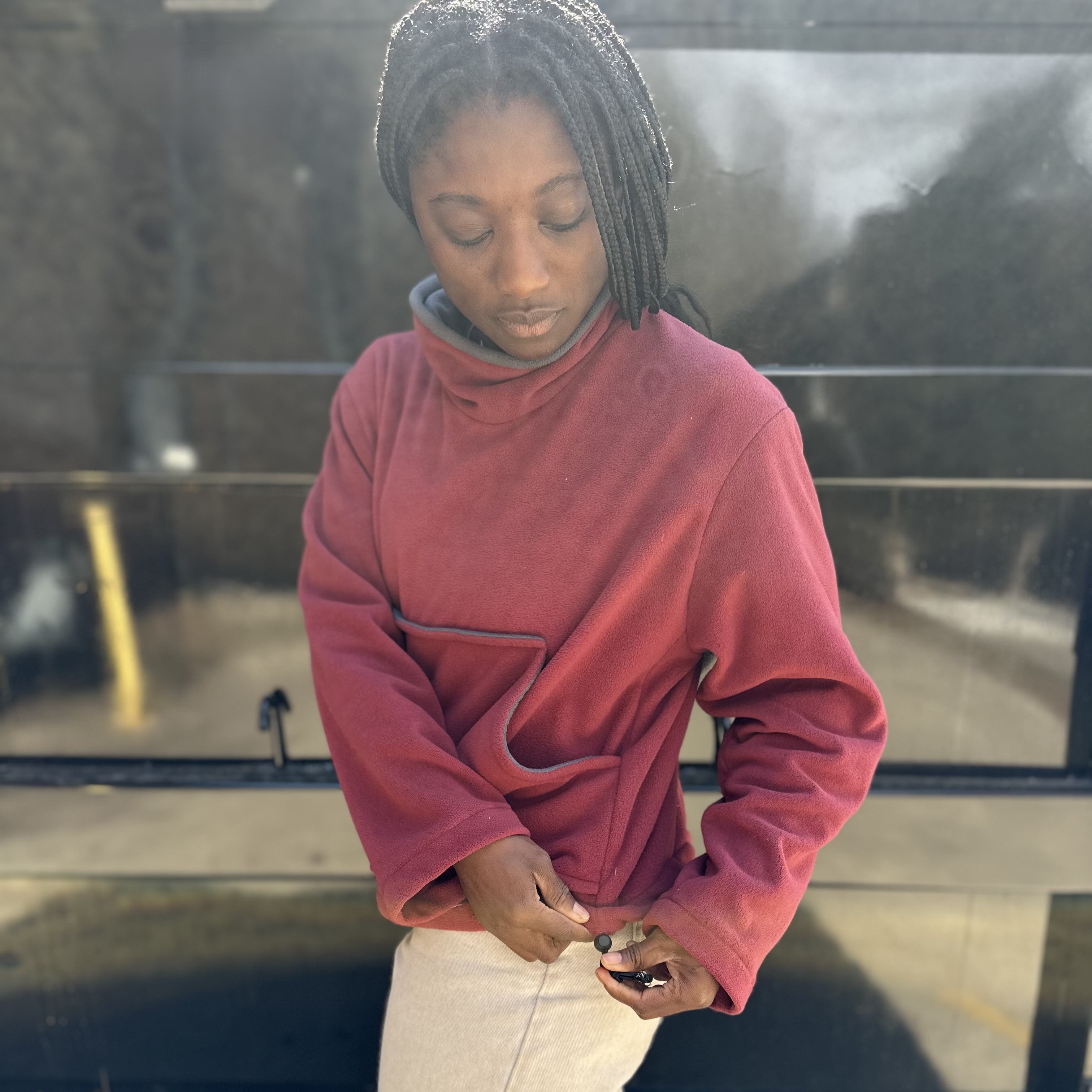 Woman in red mock sweater standing in front of black wall
