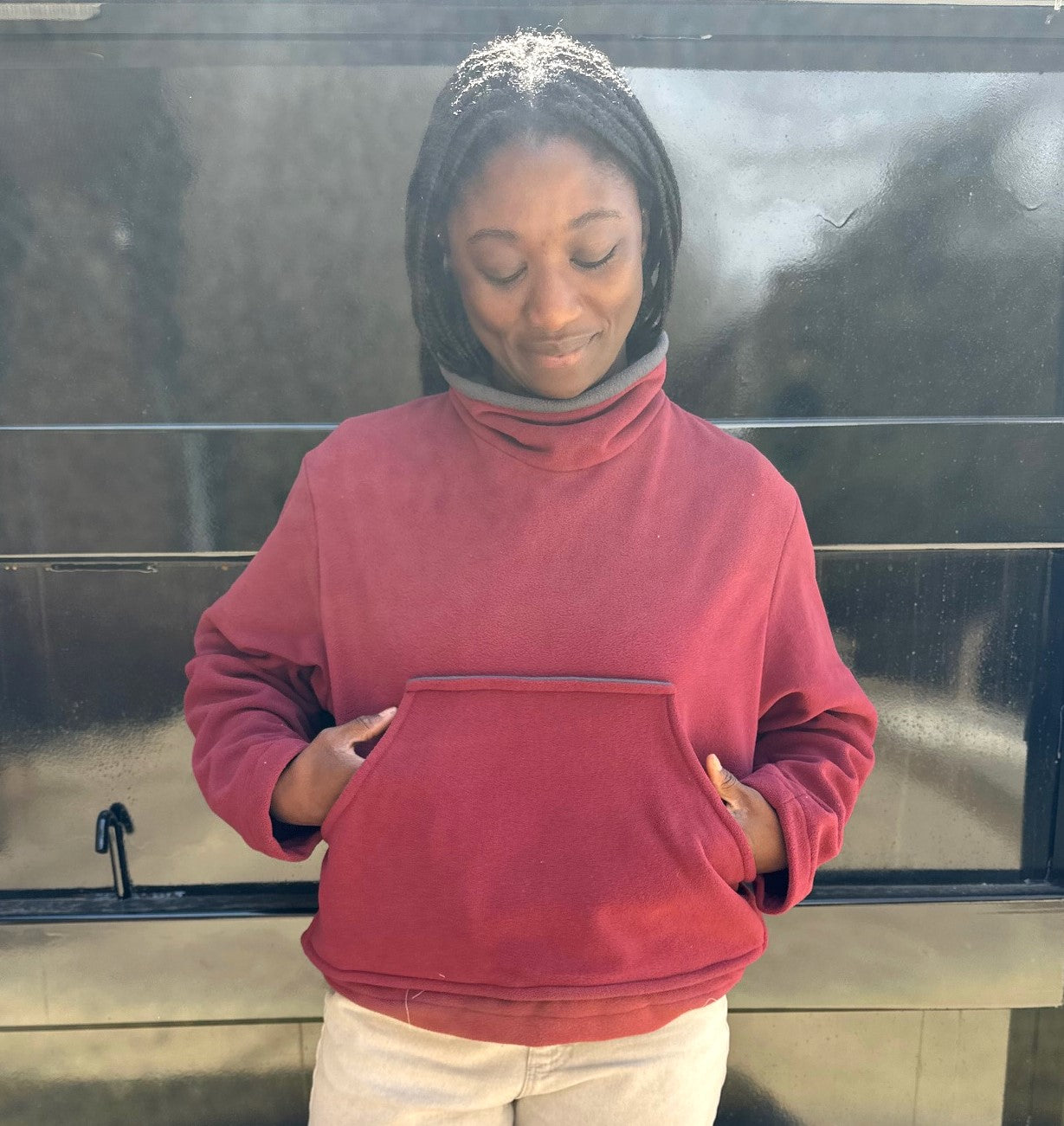 Woman in red mock sweater standing in front of black wall
