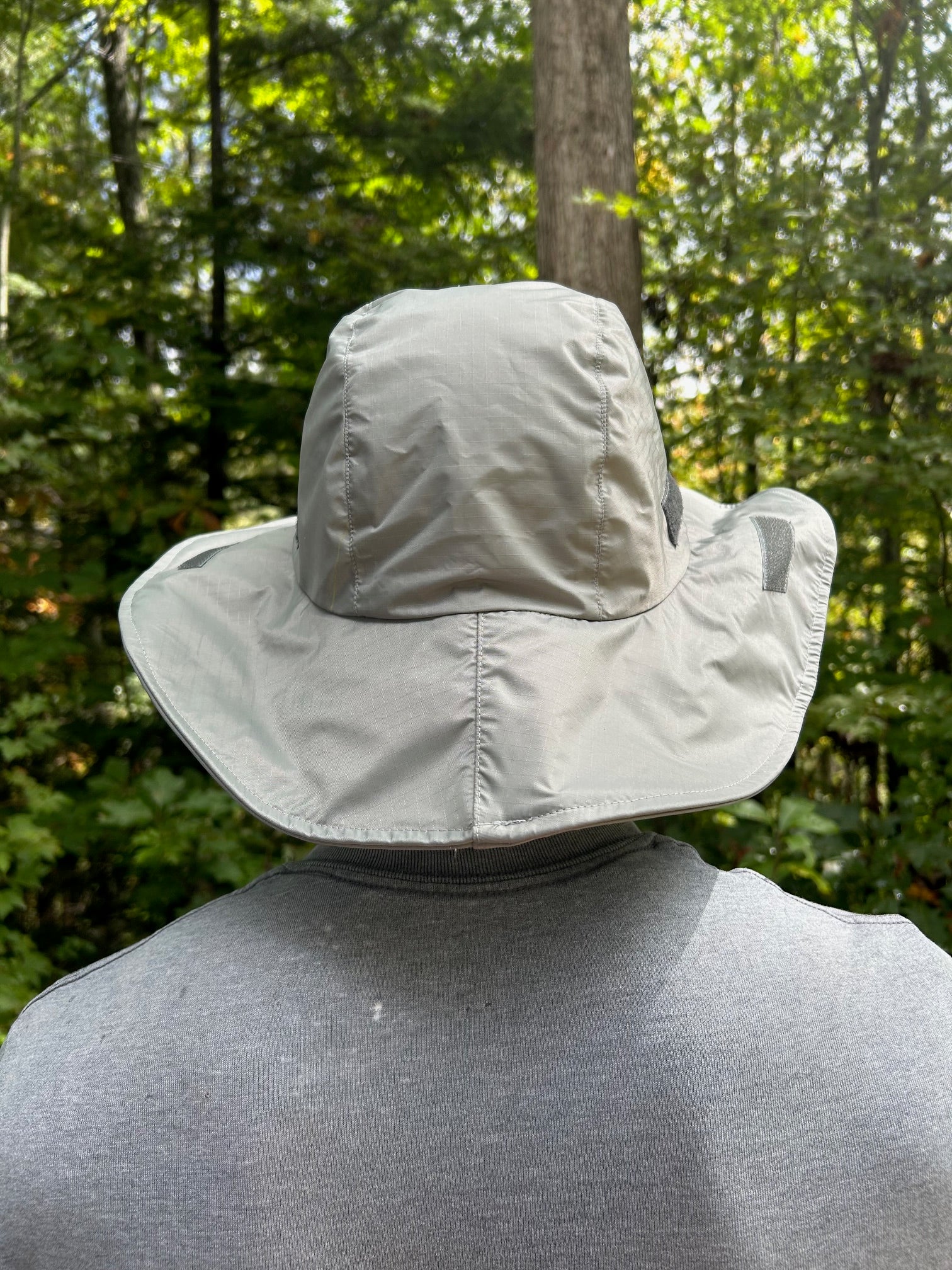 Person wearing a light-colored norwester hat in a forest setting