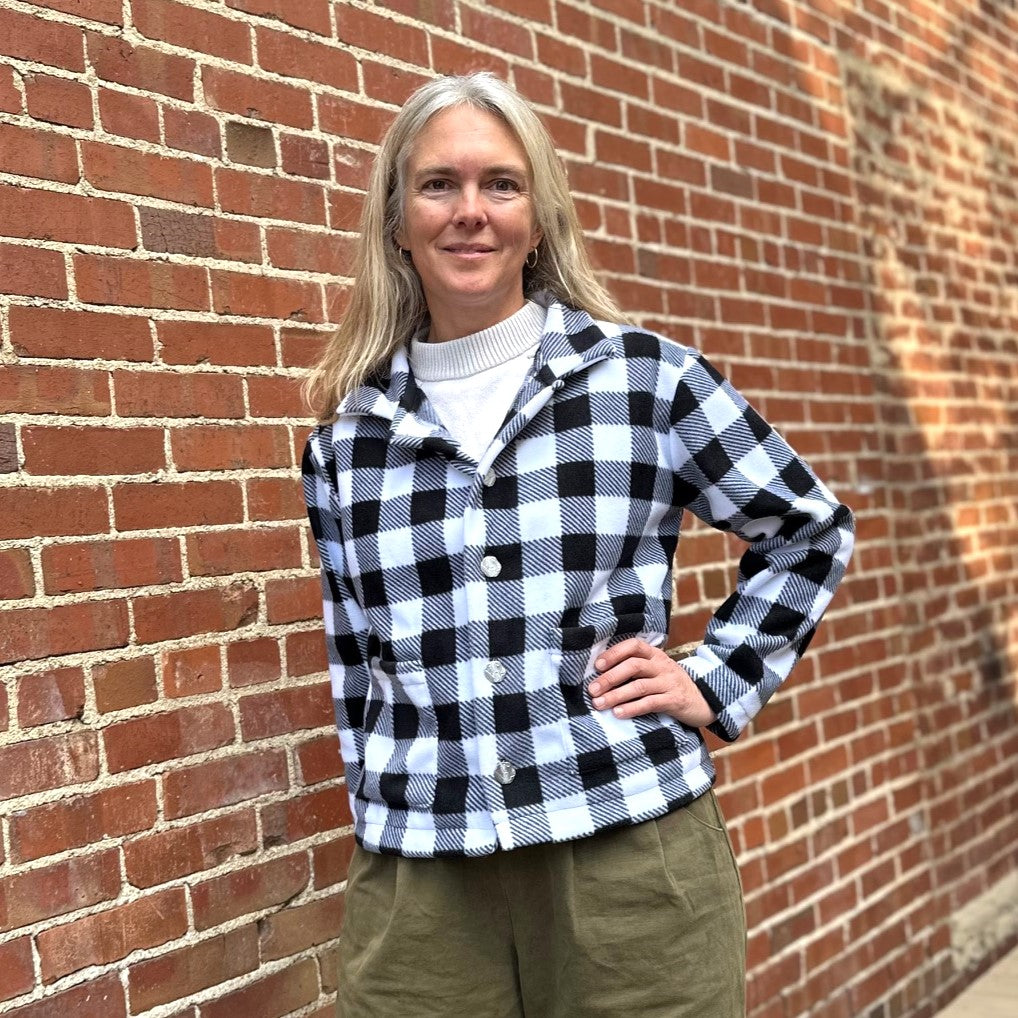 Woman standing in front of a brick wall wearing a black and white buffalo plaid polar lodge jacket.
