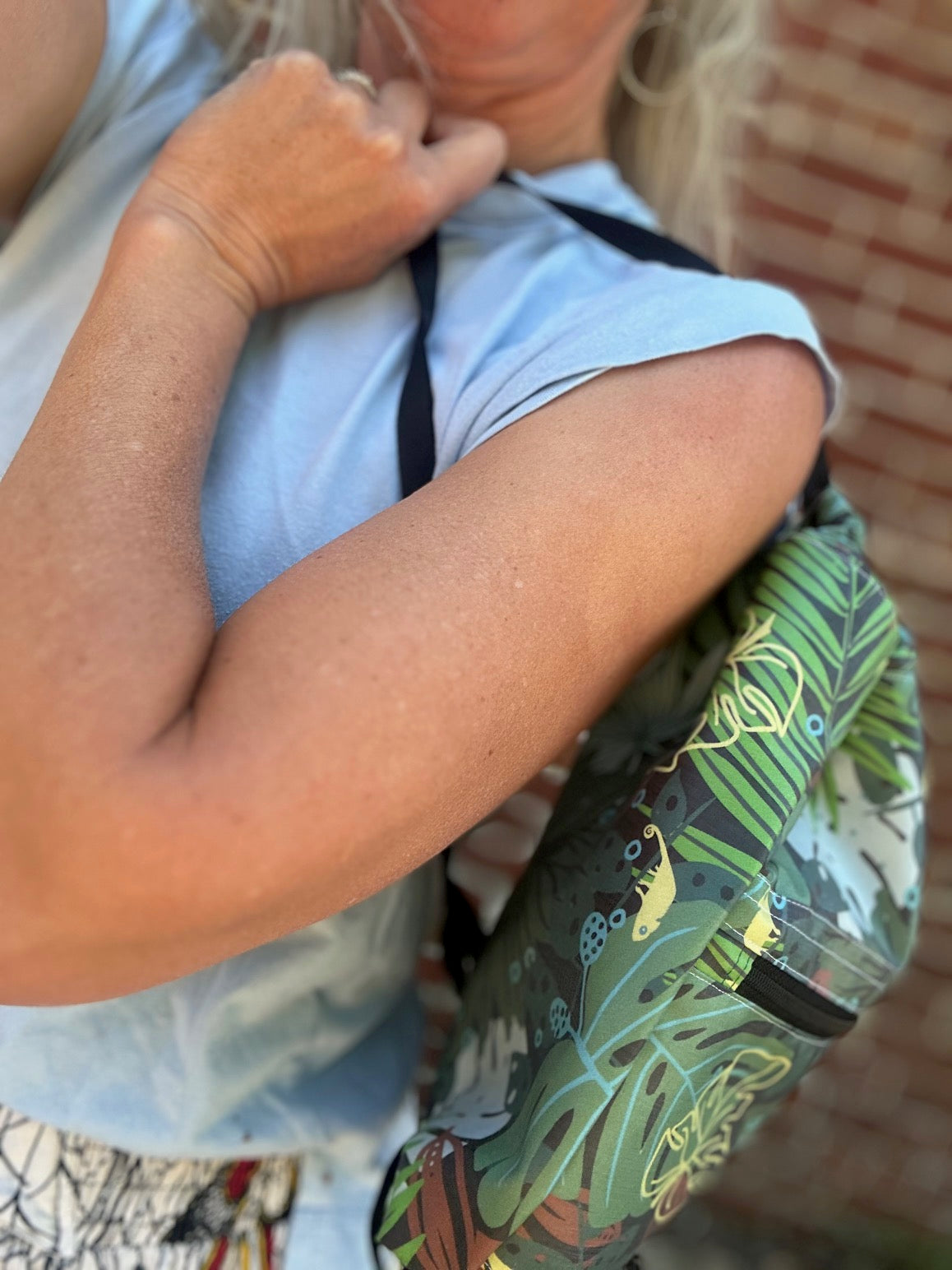 Person holding a green colorful backpack with a plant pattern.
