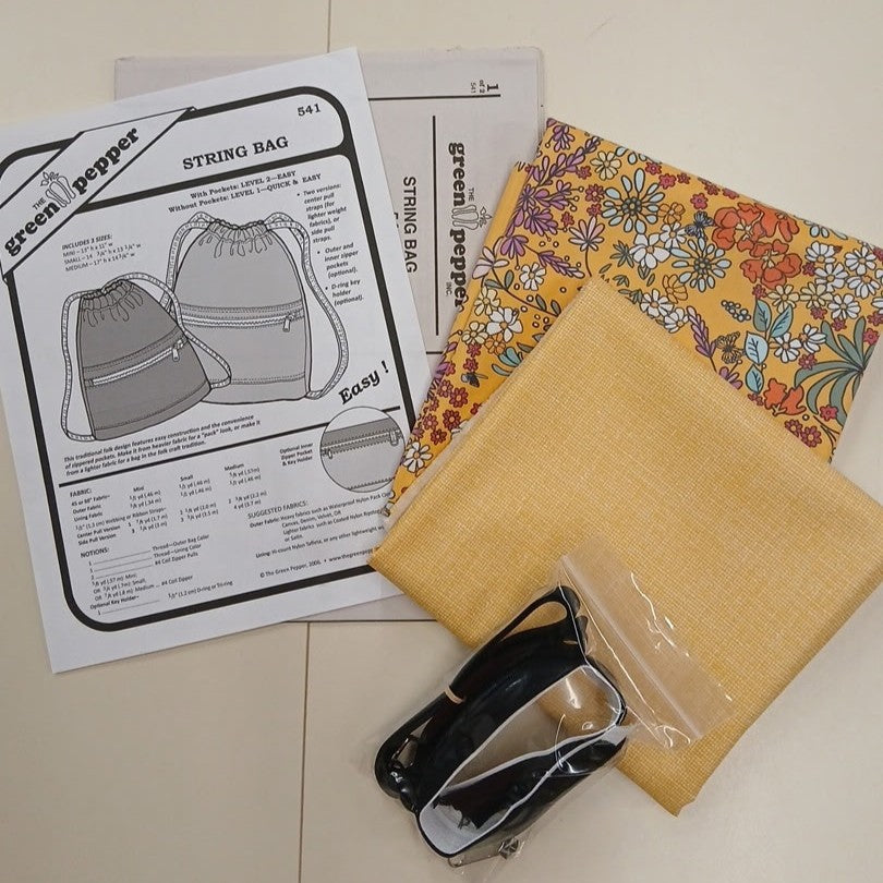 Fabric, pattern paper, and sewing tools on a tiled floor