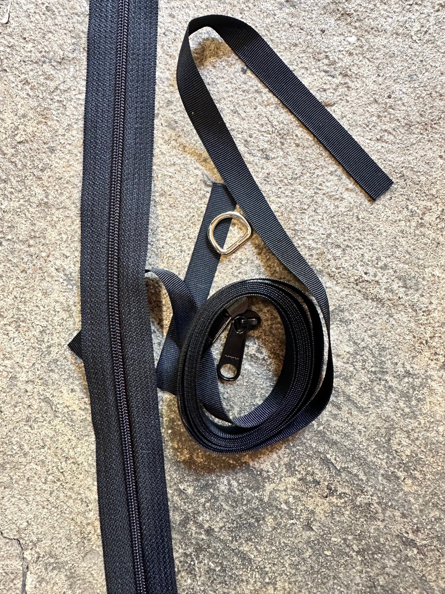 Black zippers, ribbon, and zipper pull on a textured surface