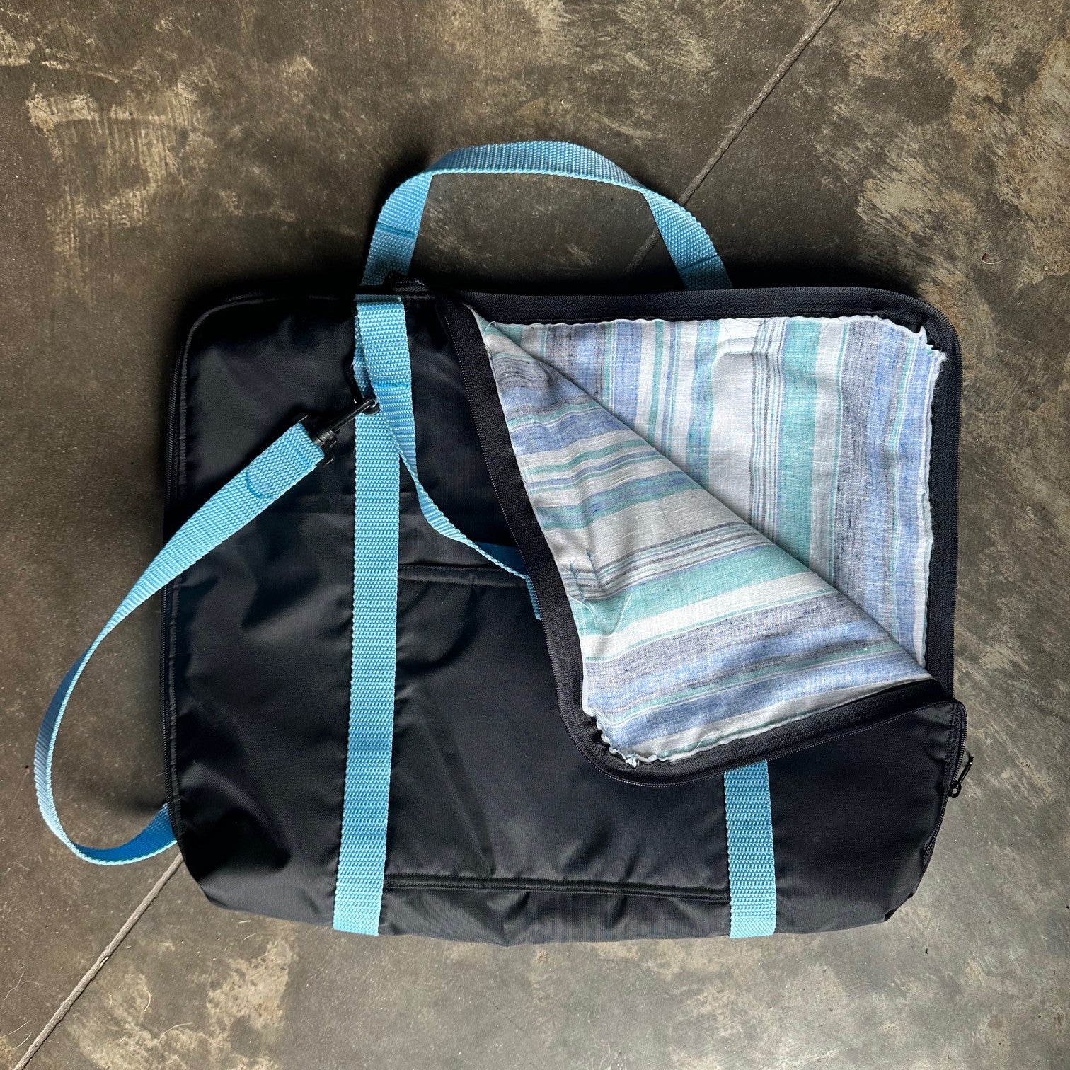 Black briefcase made with blue straps with corner folded down to show lining