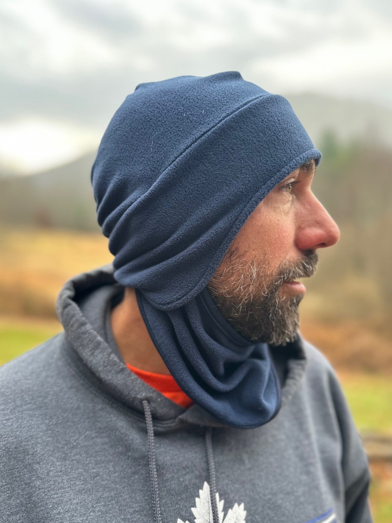 Man wearing a blue headscarf outdoors with a blurred natural background