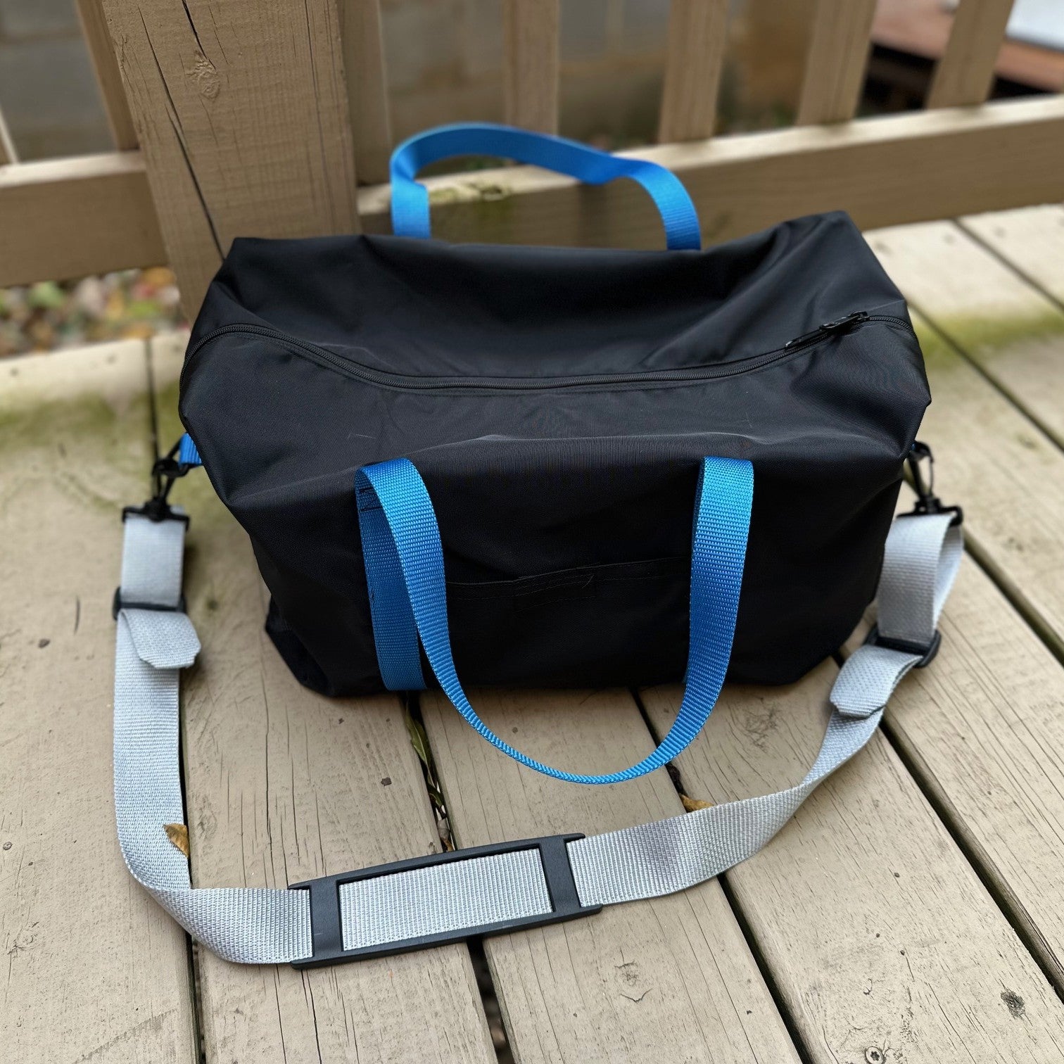 black duffel bag with blue straps and grey shoulder strap