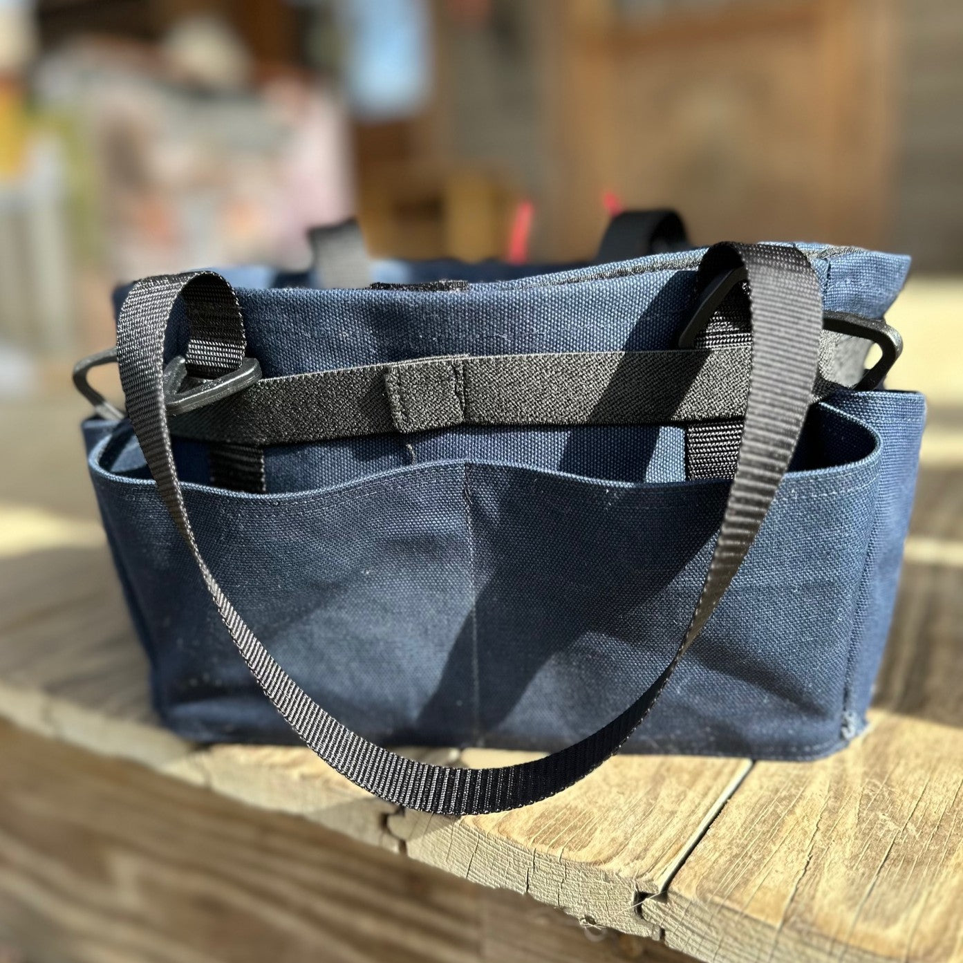 Navy blue tool caddy with straps on a wooden deck
