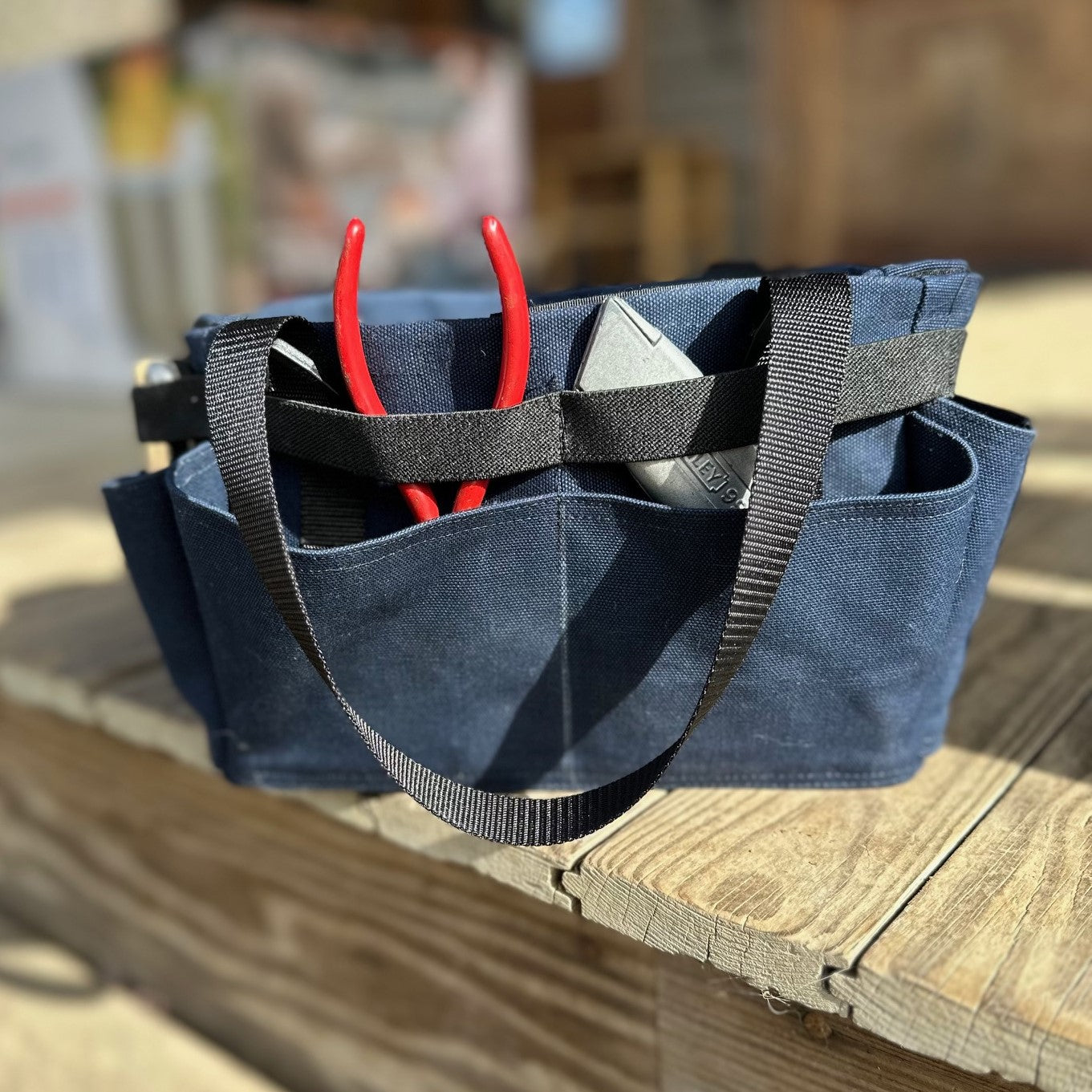 Blue tool bag with tools on a wooden surface