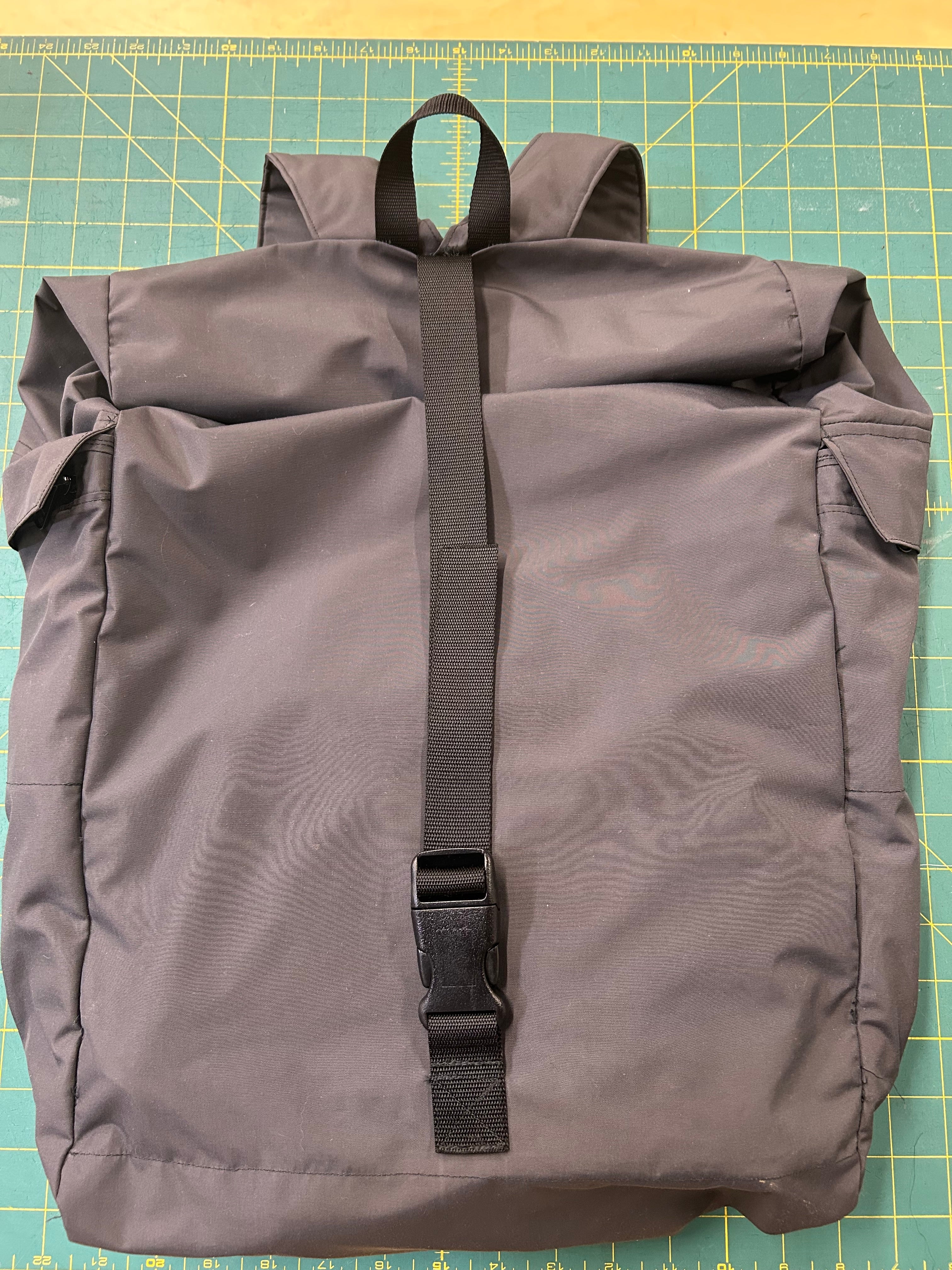 Gray bag with a black strap on a green cutting mat