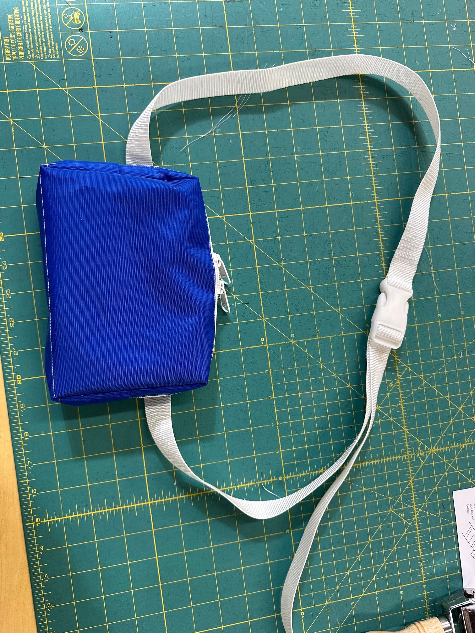Blue bag with a white strap on a green cutting mat