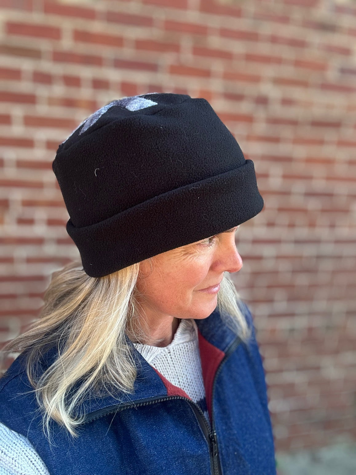 Person wearing a black Arctic Circle cap in front of a brick wall