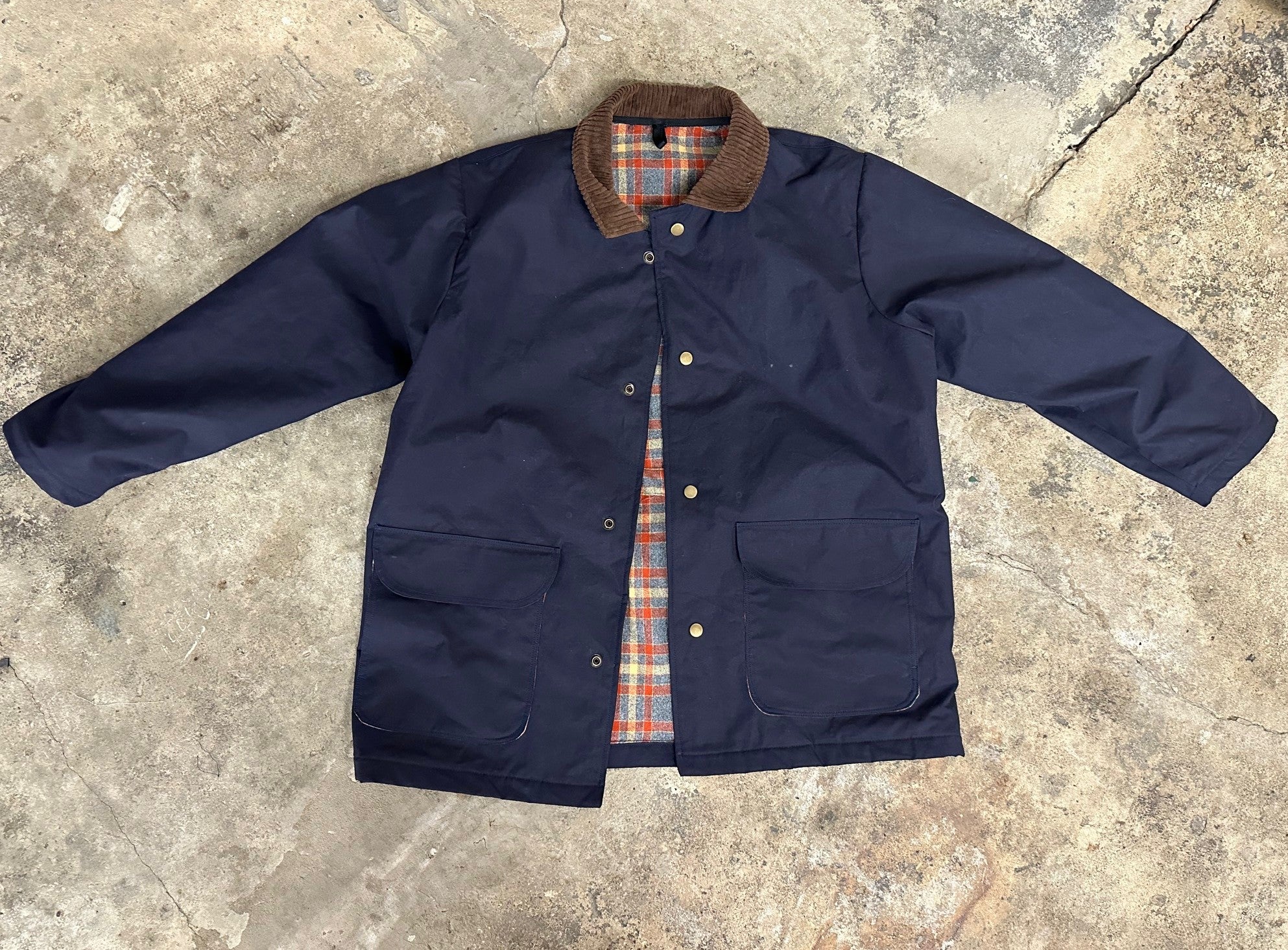 Navy jacket with plaid lining on a concrete surface