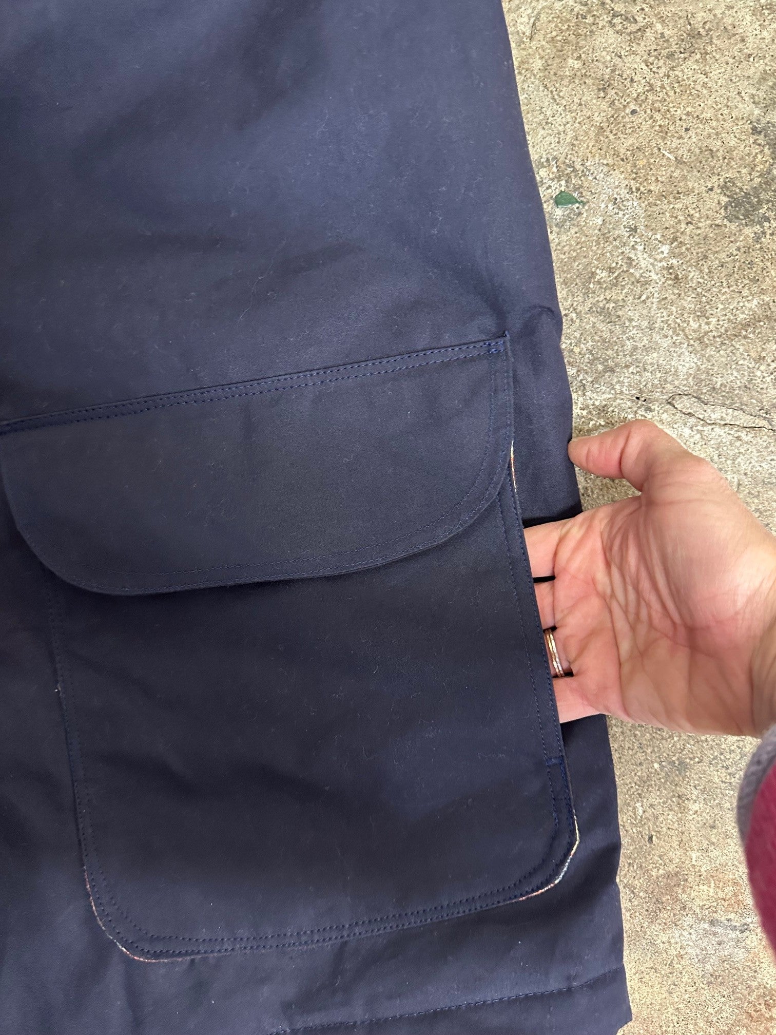 Navy blue pants with a pocket on a concrete surface