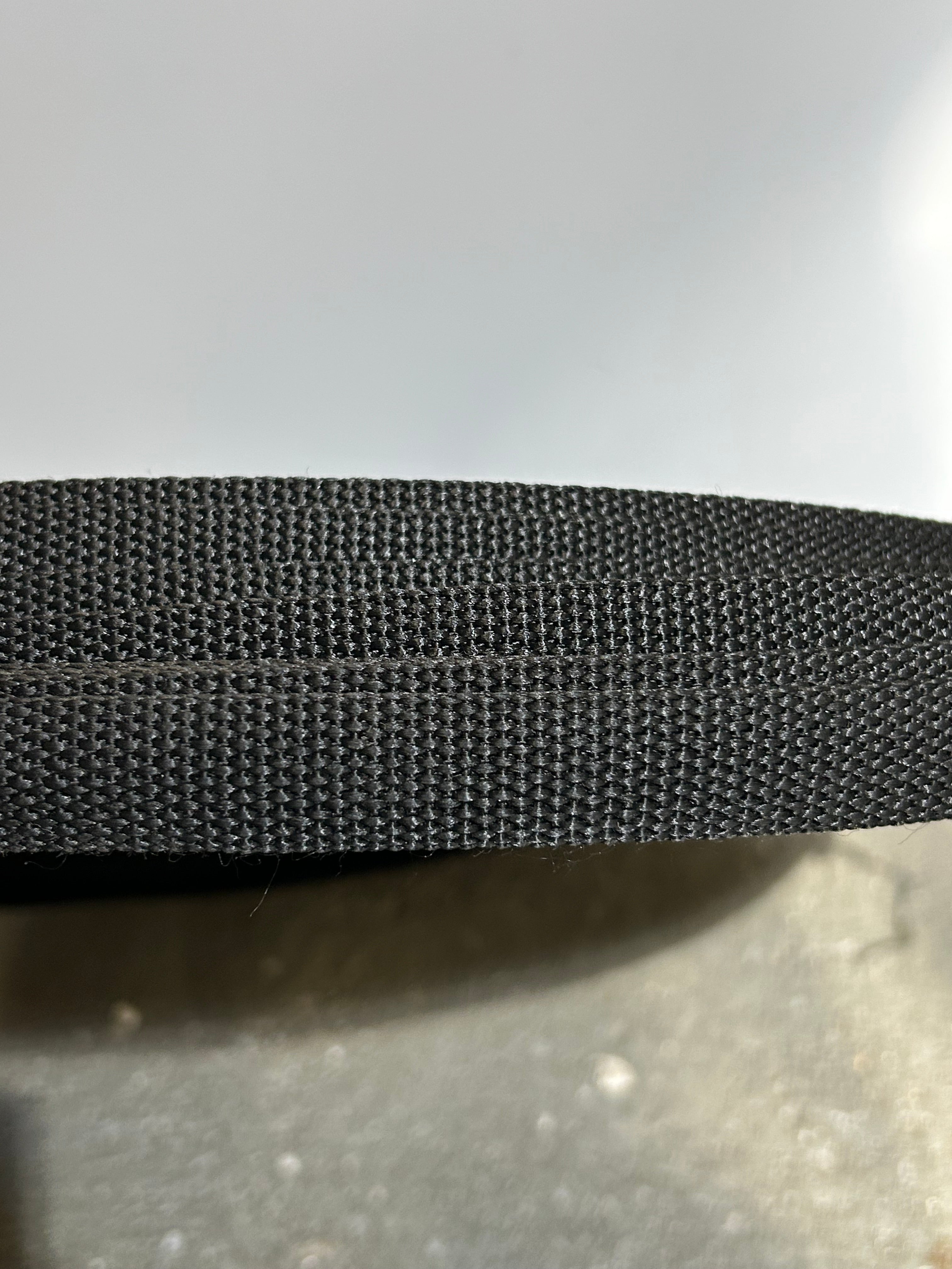 Close-up of a textured black belt on a light gray background