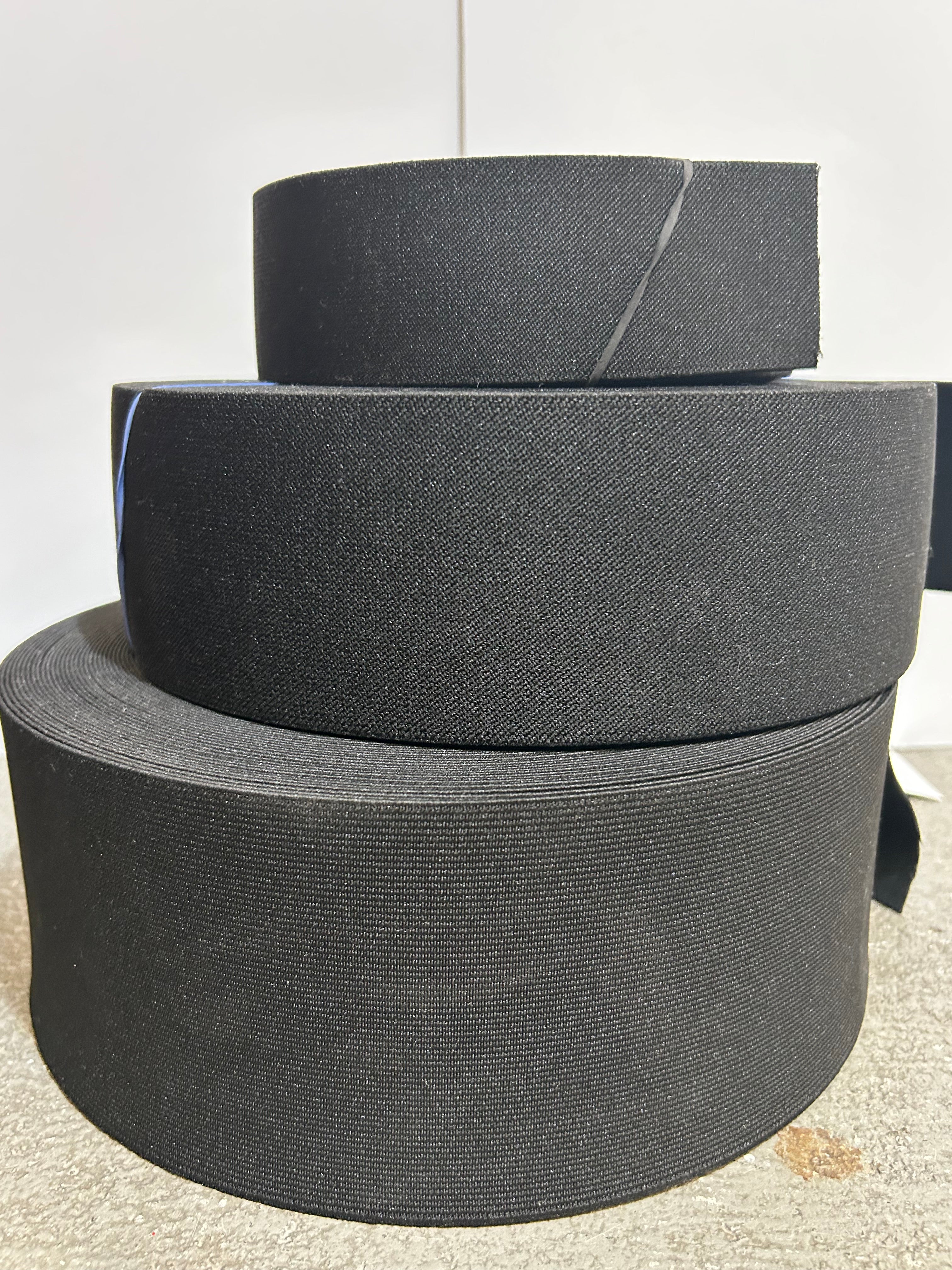 Three rolls of black webbing elastic in three difference sizes.