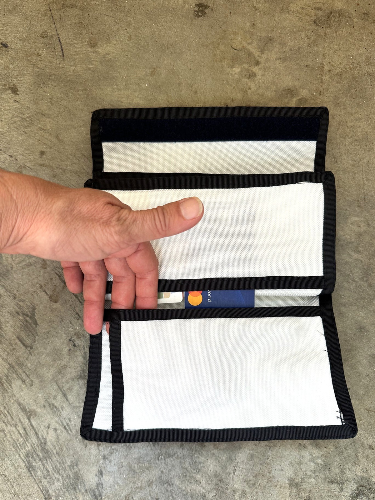 green checkbook wallet with black trim opened up on a concrete floor