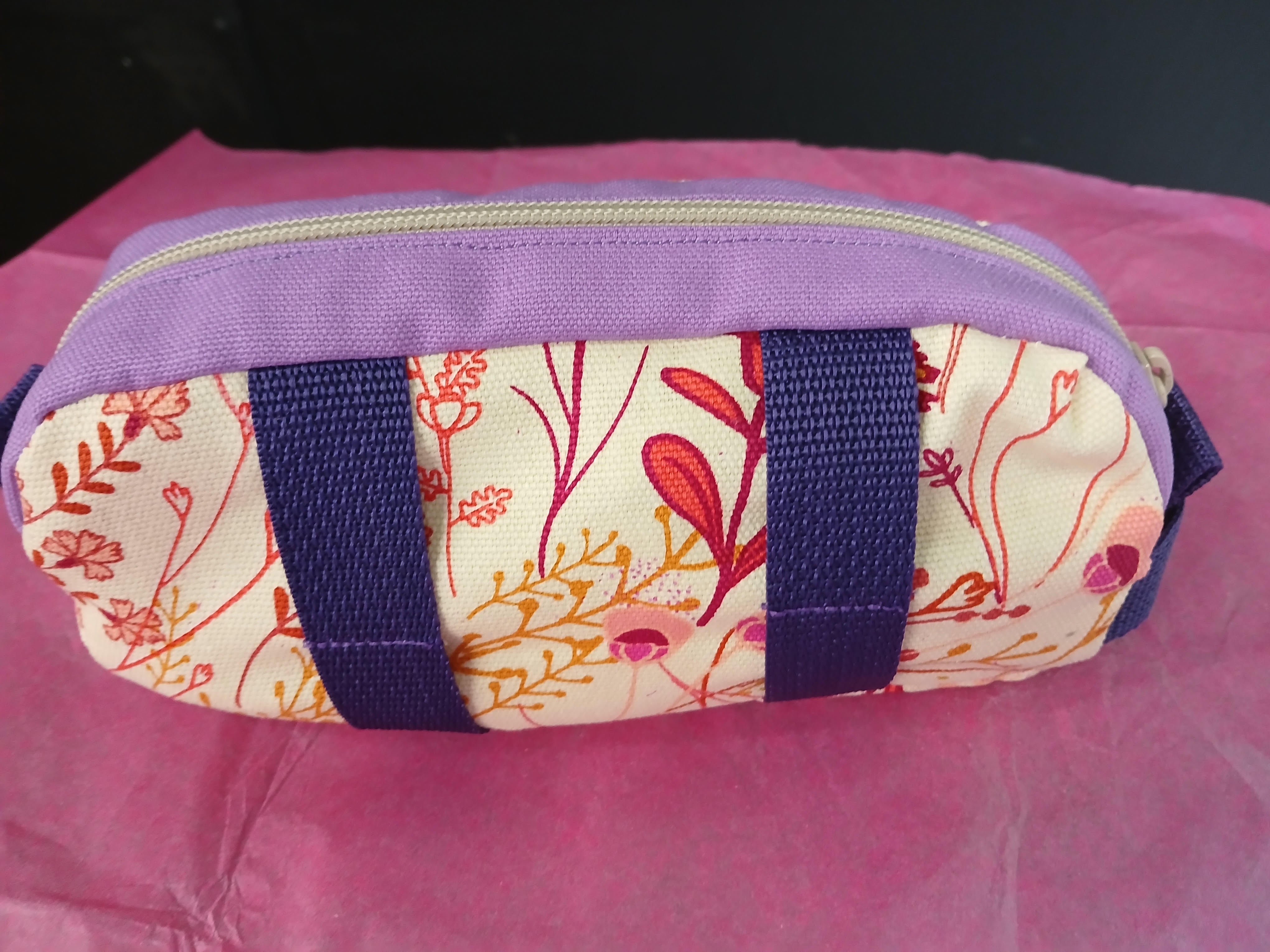 purple and floral print dopp kit with purple webbing on pink tissue