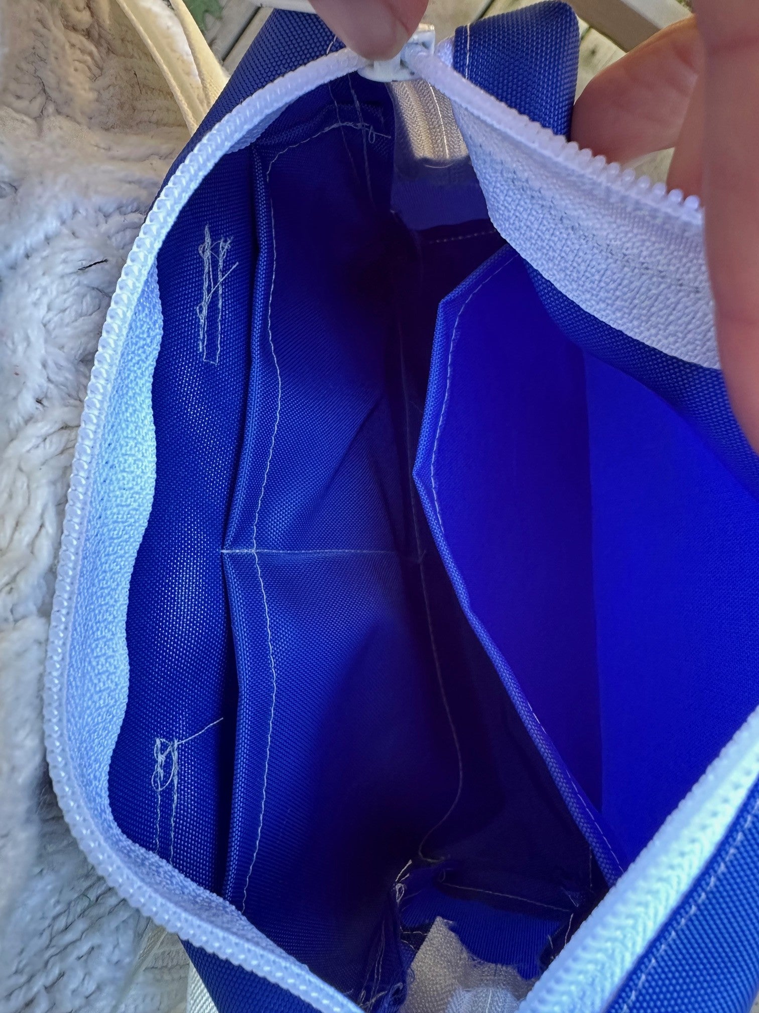 Close-up of the inside of a blue bag with white trim being held open.