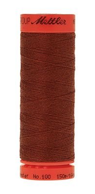 A spool of Muttila sewing thread in a warm rust-brown color, with a bright orange-red plastic spool showing the Muttila brand name.