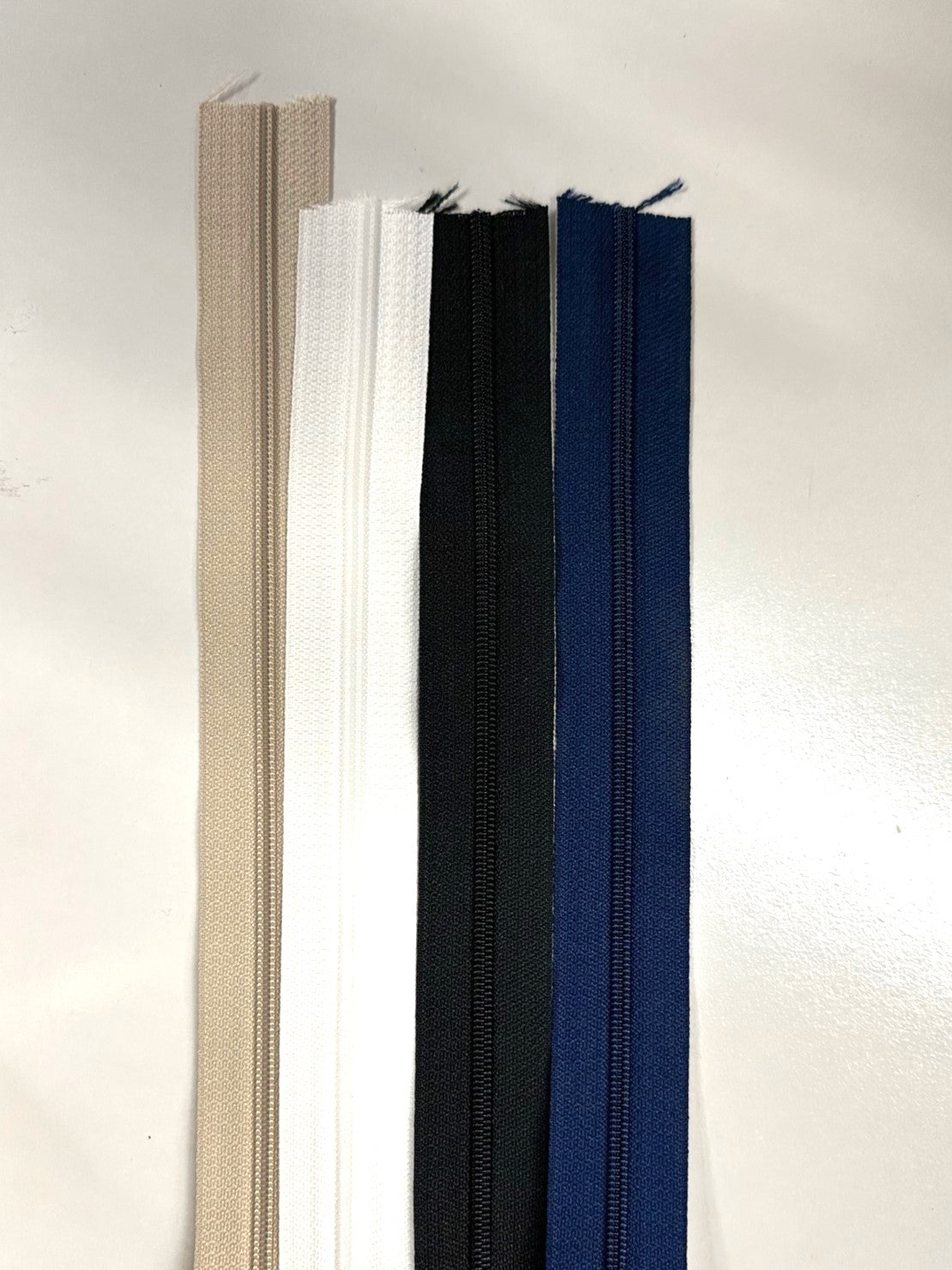 Coil zipper tape by the yard in beige, white, black, and navy