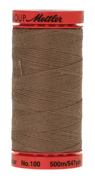 A spool of Mettler sewing thread in a warm brown shade, wound on a red plastic spool with black printed text.