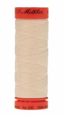 A spool of Mettler sewing thread in a light cream color, featuring a bright red-orange plastic spool with black printed branding.