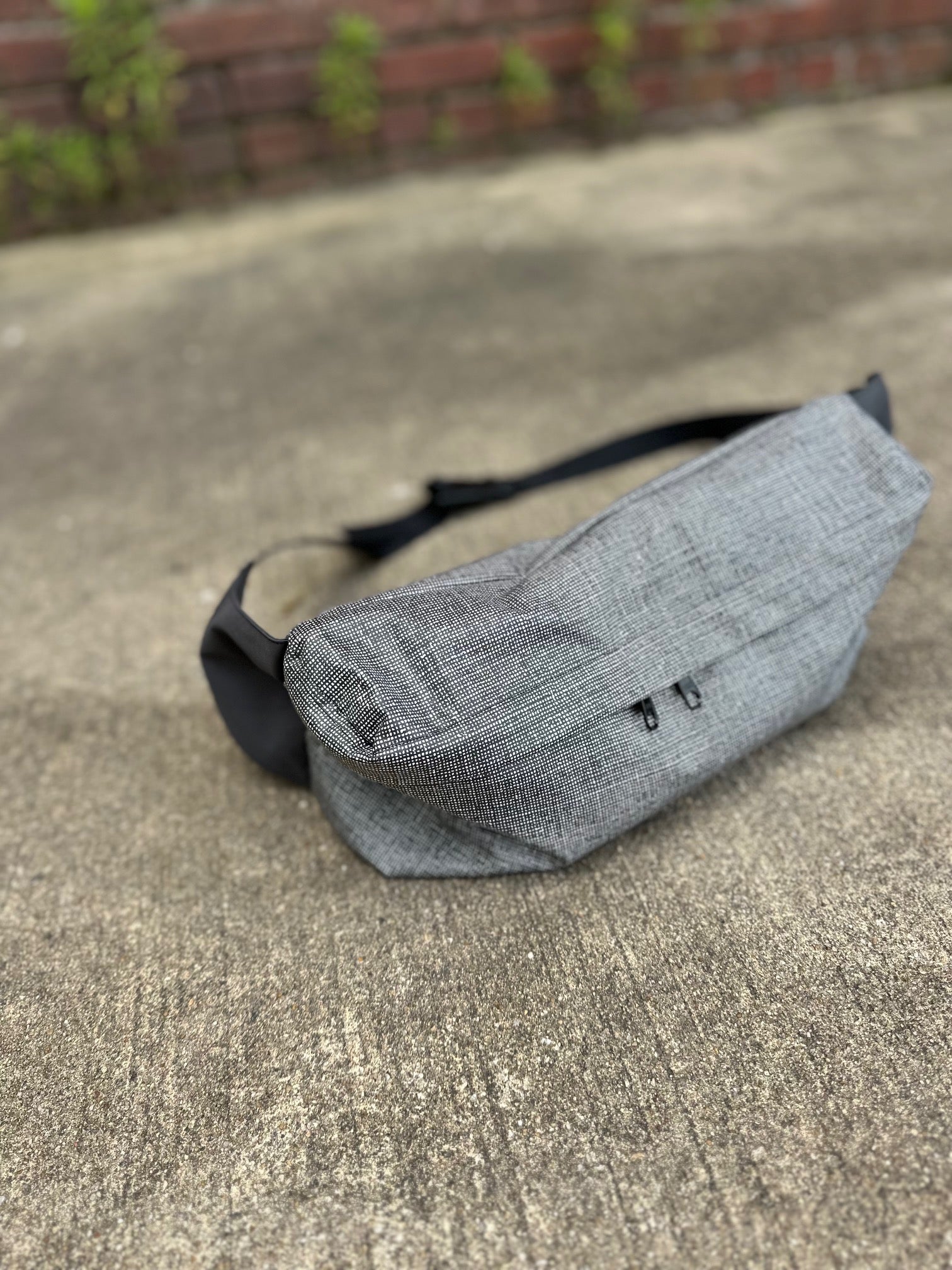 Gray waist bag on a concrete surface with a blurred background